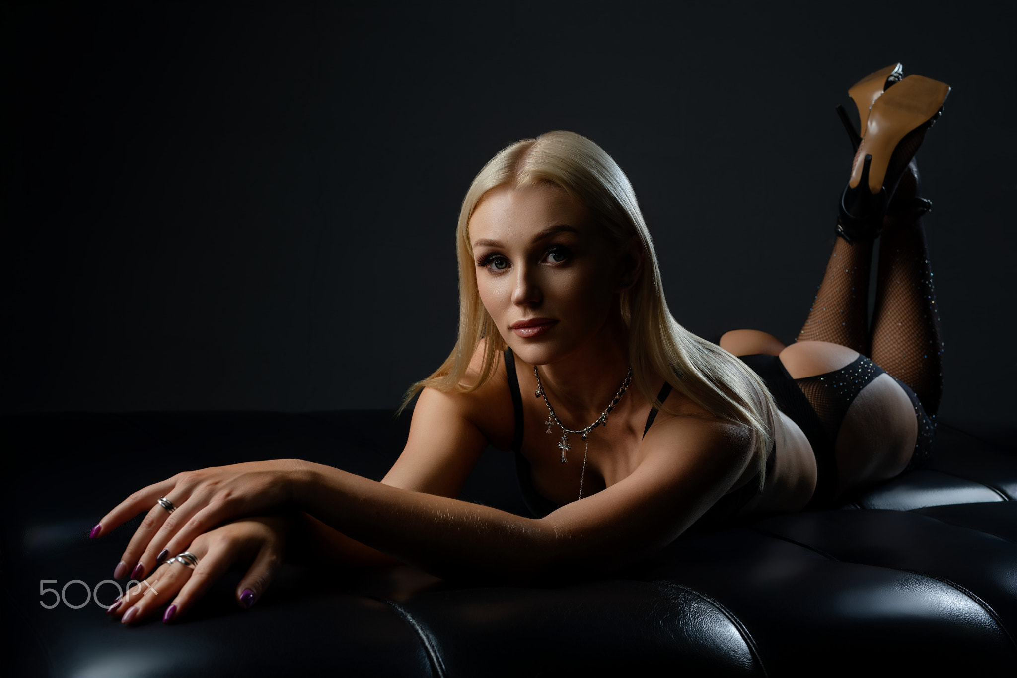 Elegant model in black lingerie poses on a couch during a low-light session