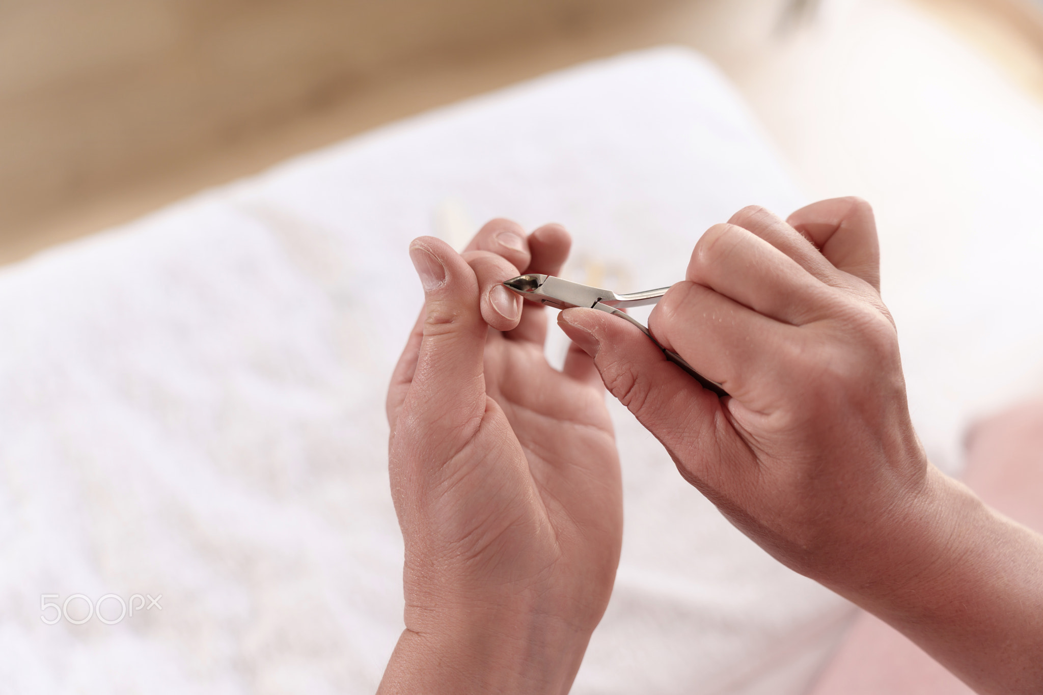 Women's hands trimming cuticles using cuticle clippers to maintain healthy and beautiful nails.