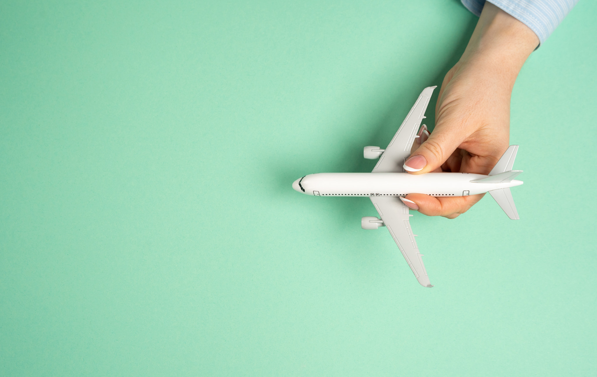 Passenger plane in girl's hand and empty background for text. Concept of flights and travels. Touris