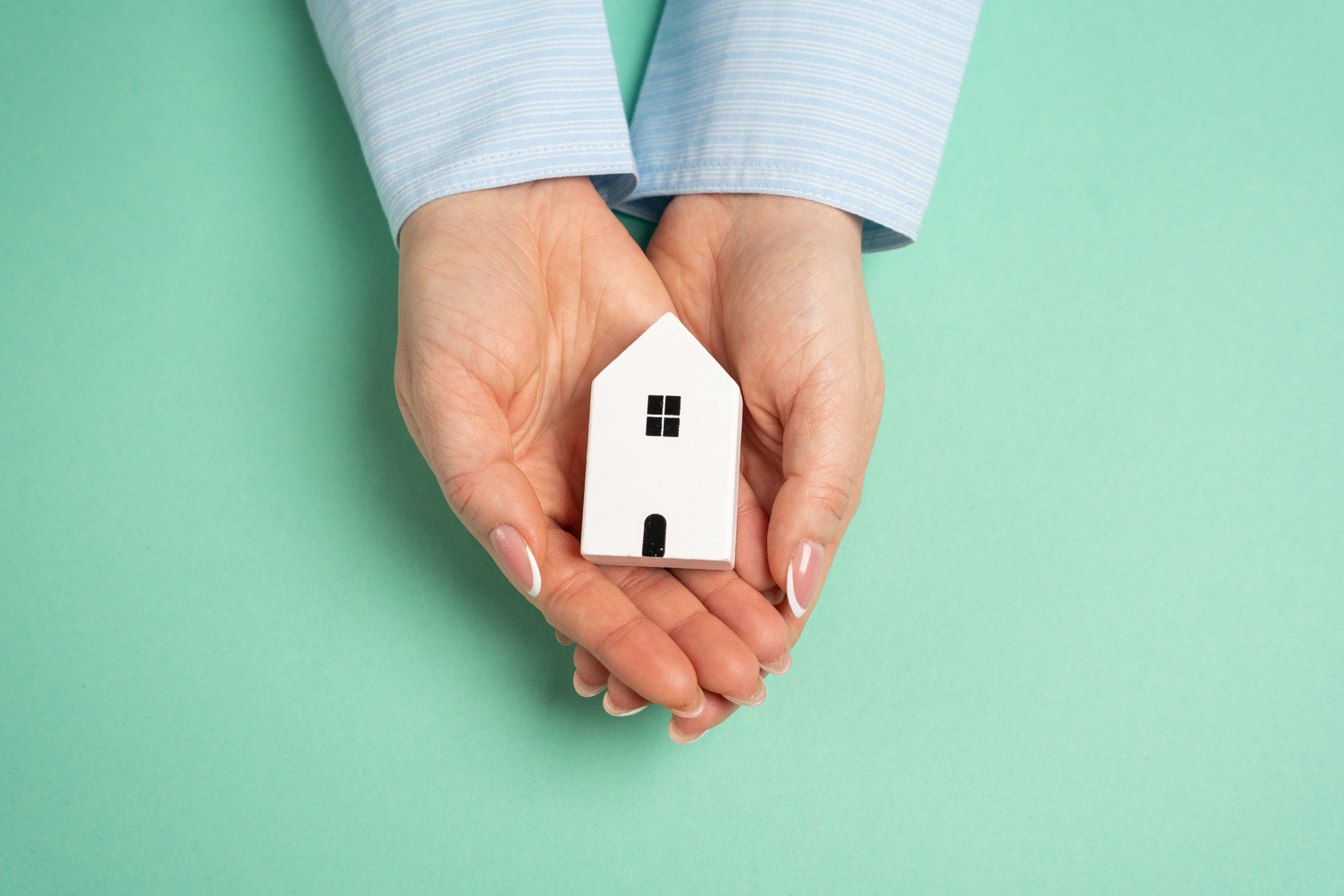 A figurine of a house in the palms of a hand. Concept of own home. Homeownership, property investmen