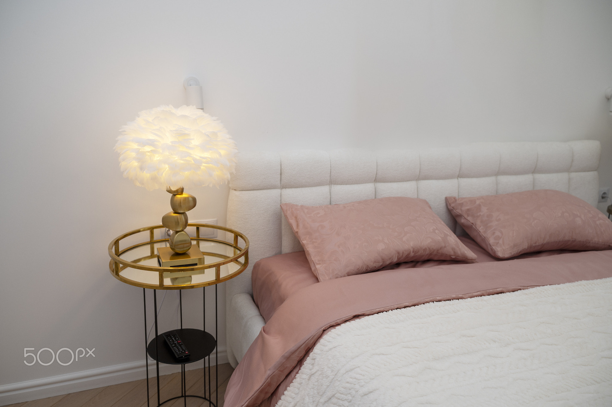 White double bed with dark pink bed linen and white blanket.