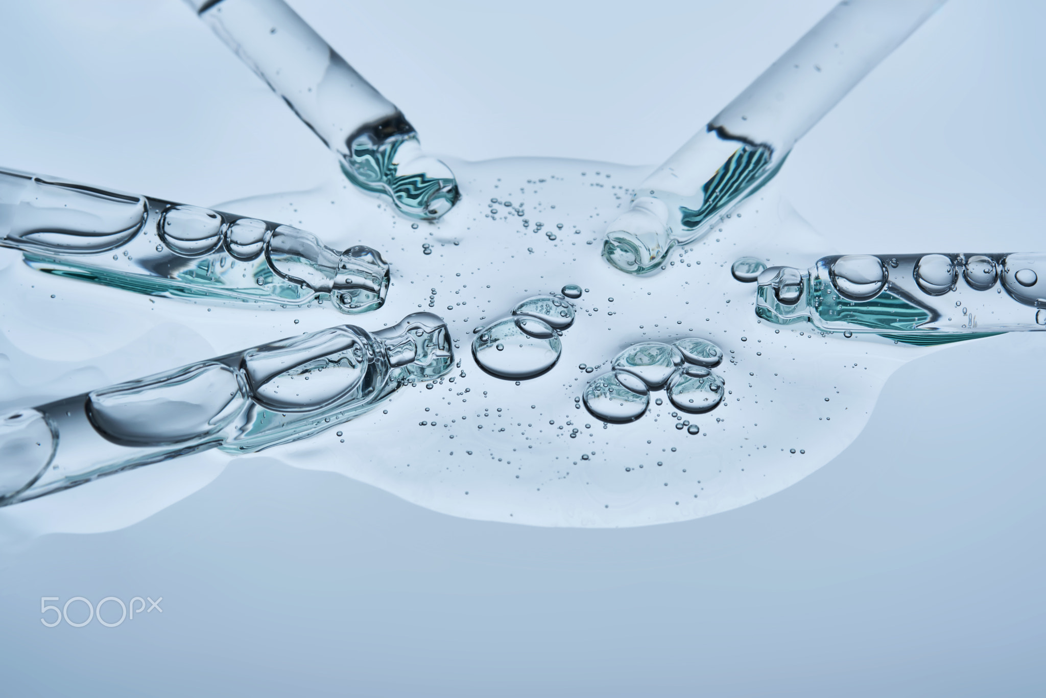 The serum flows from several pipettes into a single texture on a blue background.