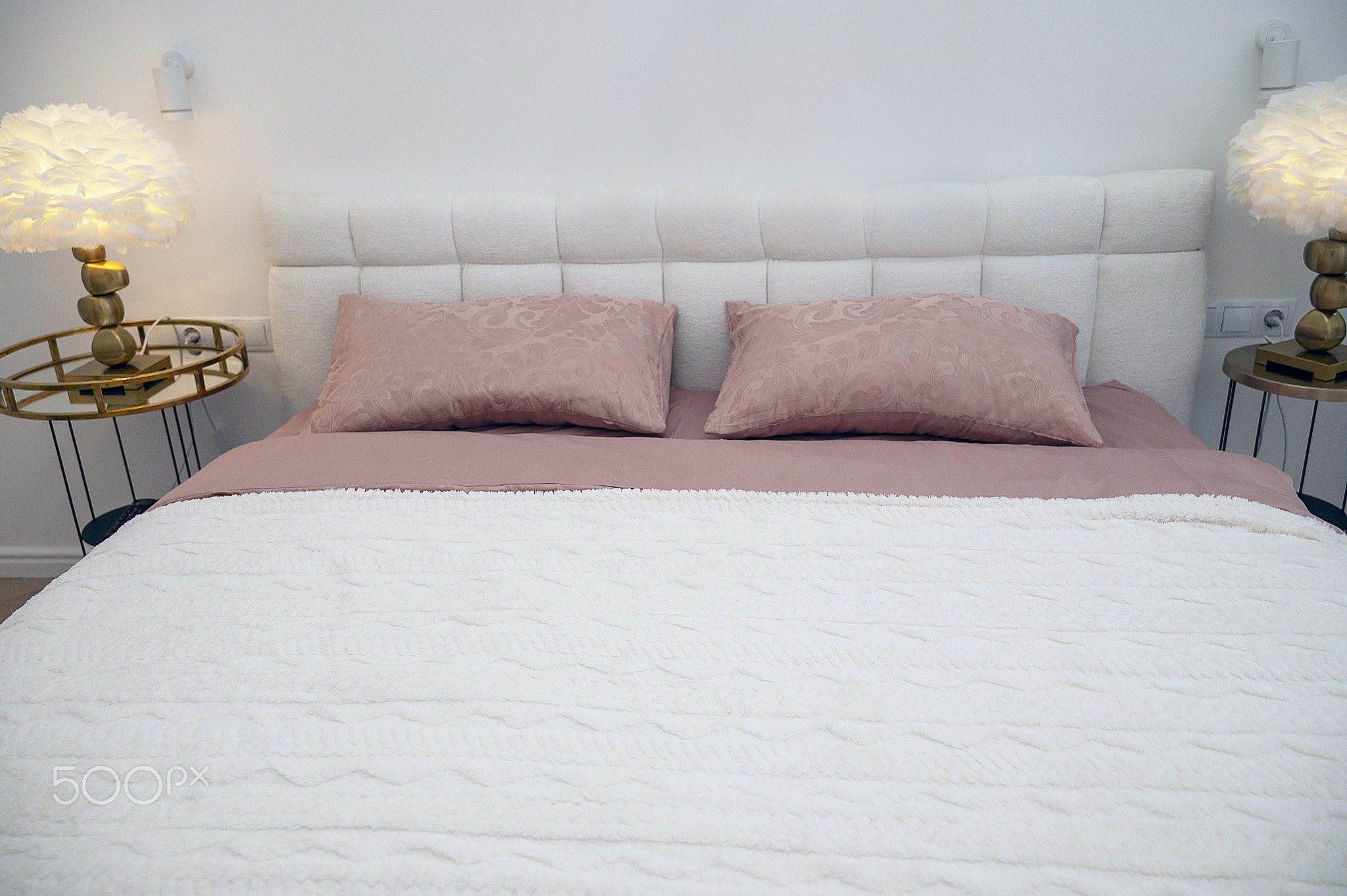 White double bed with dark pink bed linen and white throw