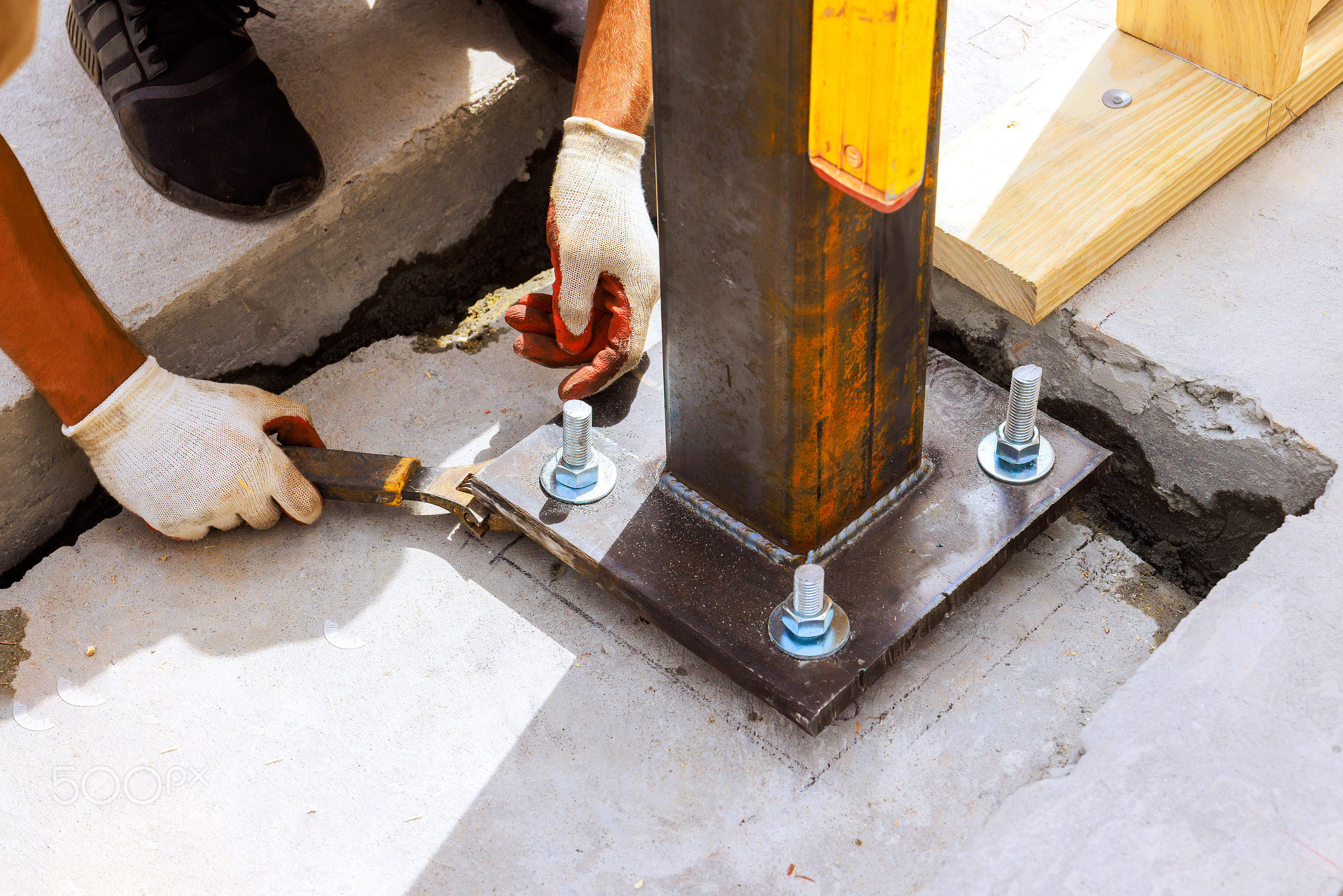 Worker secures steel column on construction site using tools fasteners