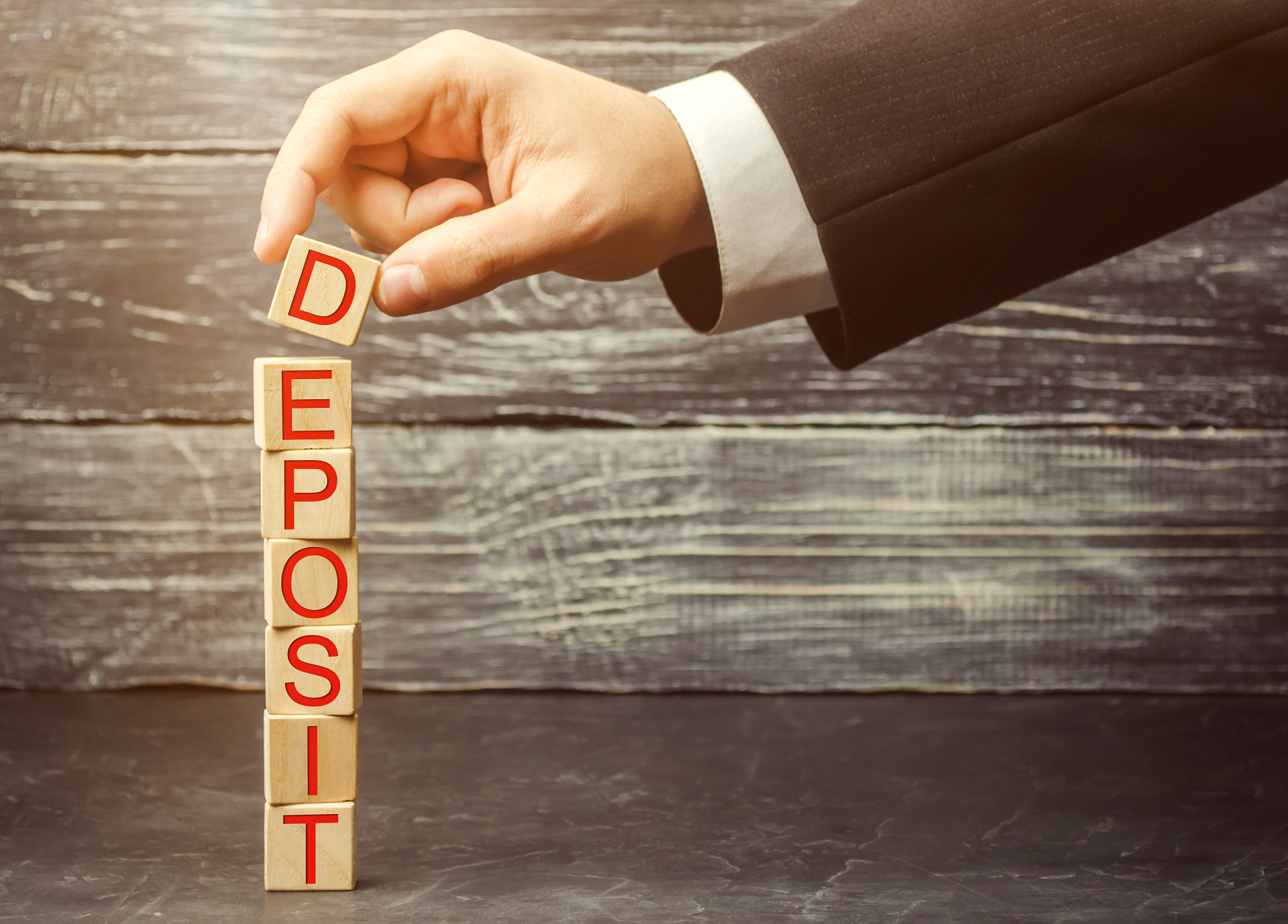 Businessman puts wooden blocks with the word deposit. Concept of investing money in a bank at a perc