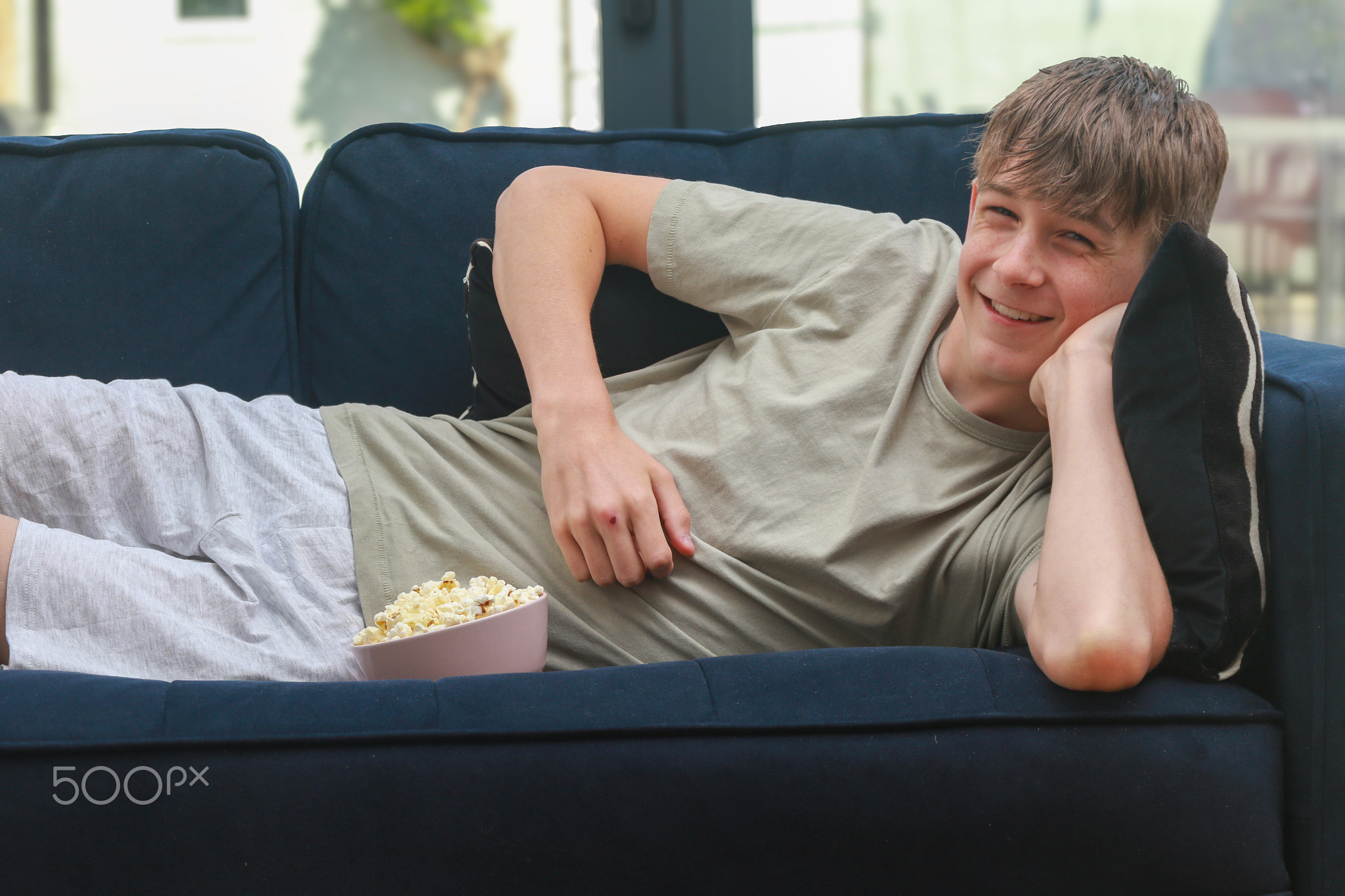 Teenage boy on a sofa Eating Popcorn