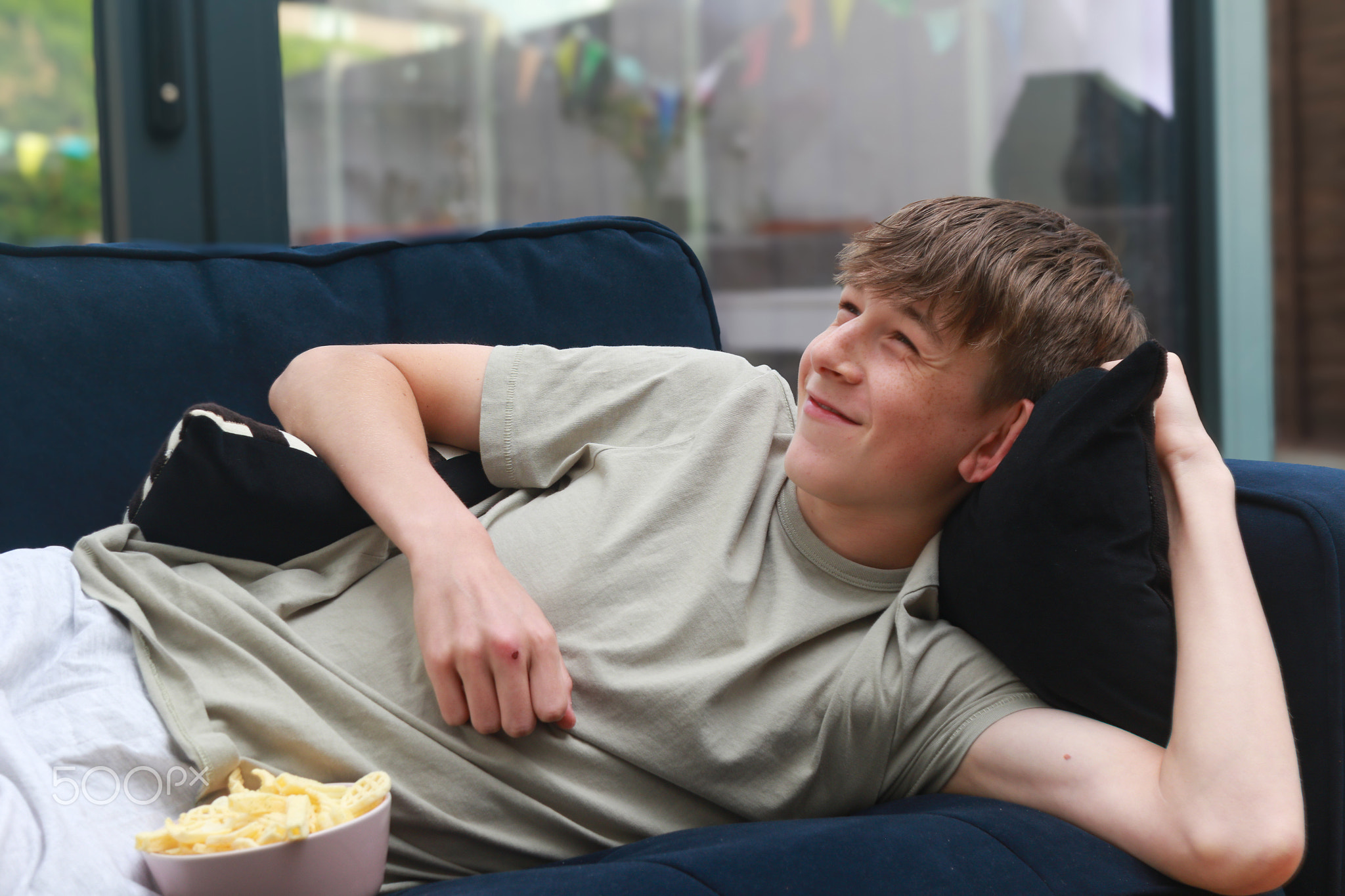 Teenage boy on a sofa with snacks