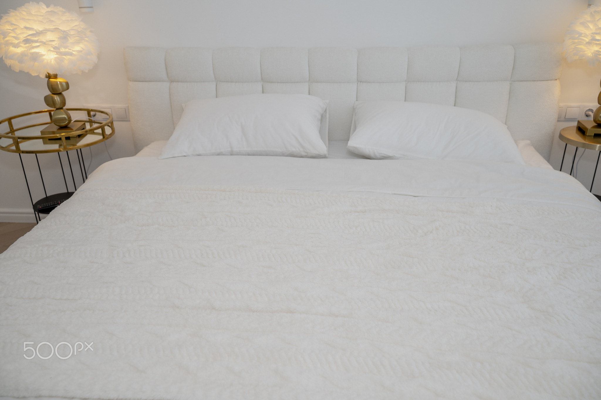A cozy, modern hotel room with a neatly made white bed. The room is decorated in a minimalist style