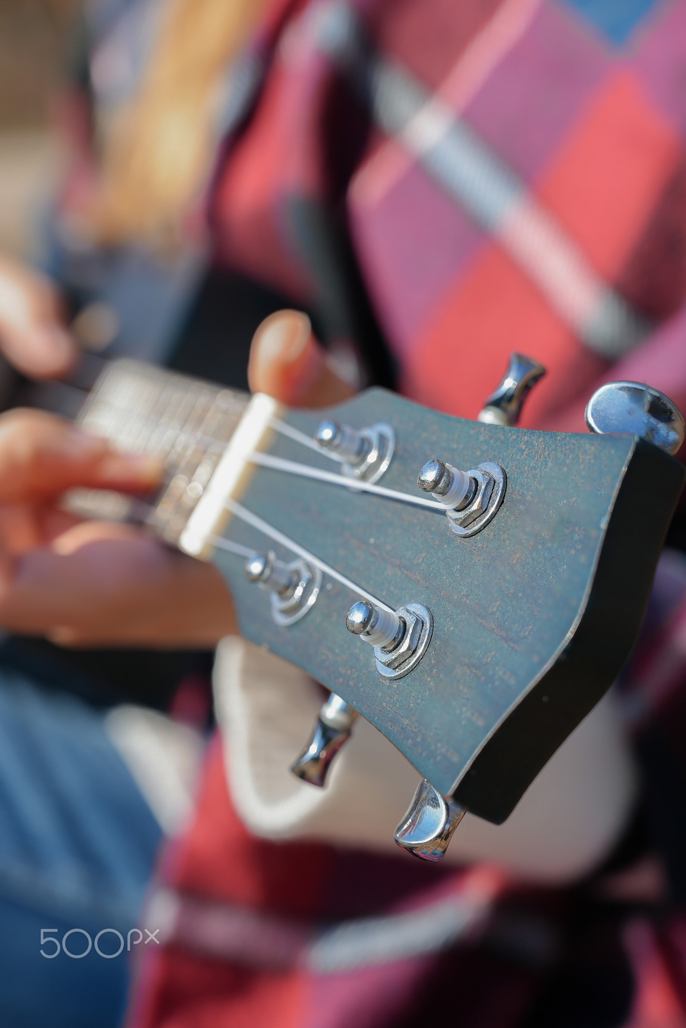 Close up of female hands play ukulele in autumnal park. Young woman