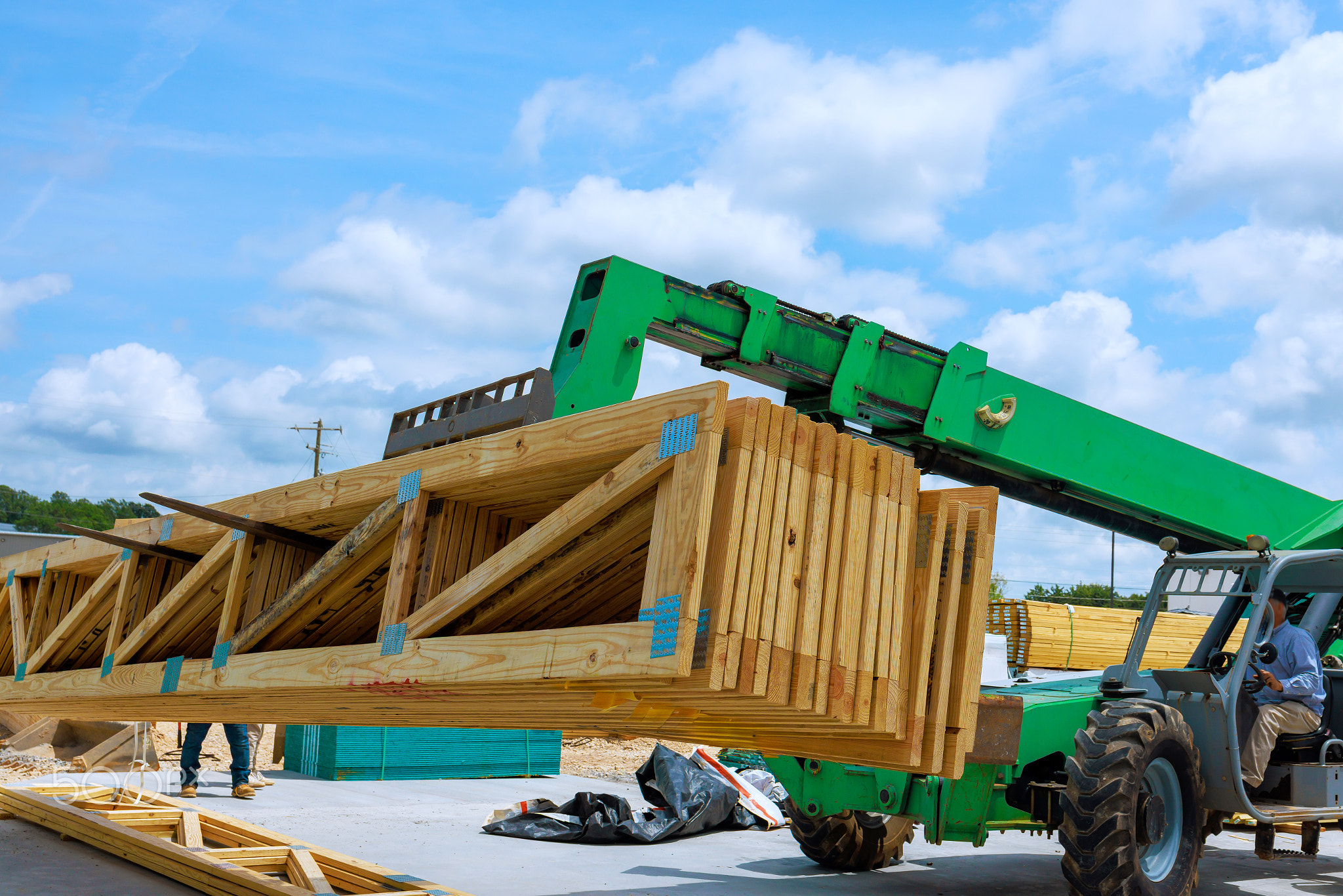 Construction workers using machinery to lift wooden beams at building