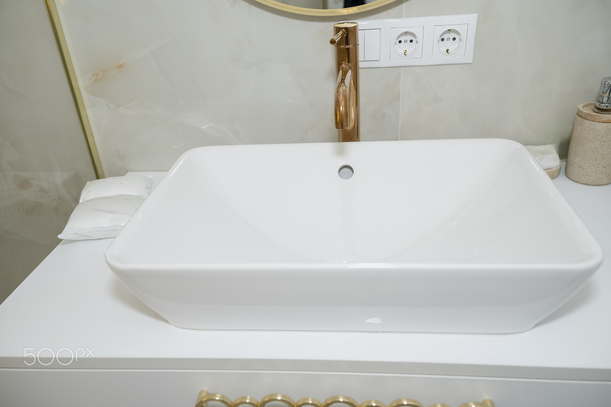 Modern bathroom with white rectangular sink, gold faucet and marble tiles