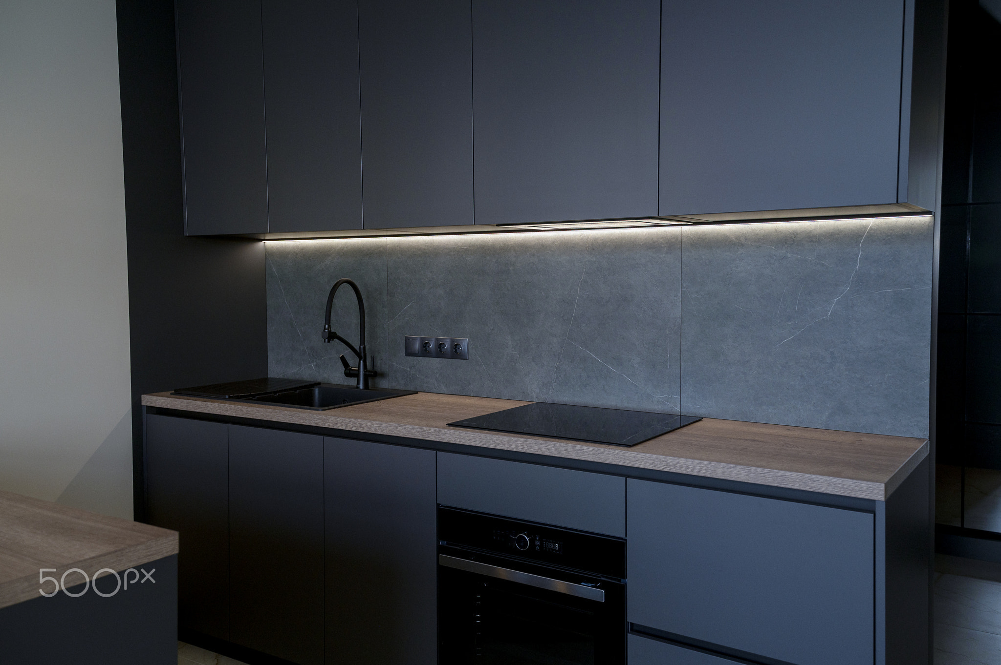 Contemporary kitchen with a black induction cooktop, built-in oven and lighting