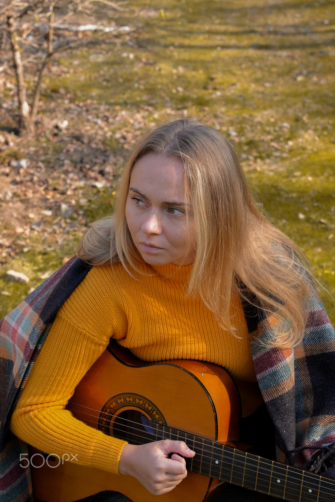 Portrait of smiling caucasian artist plays wooden acoustic guitar in