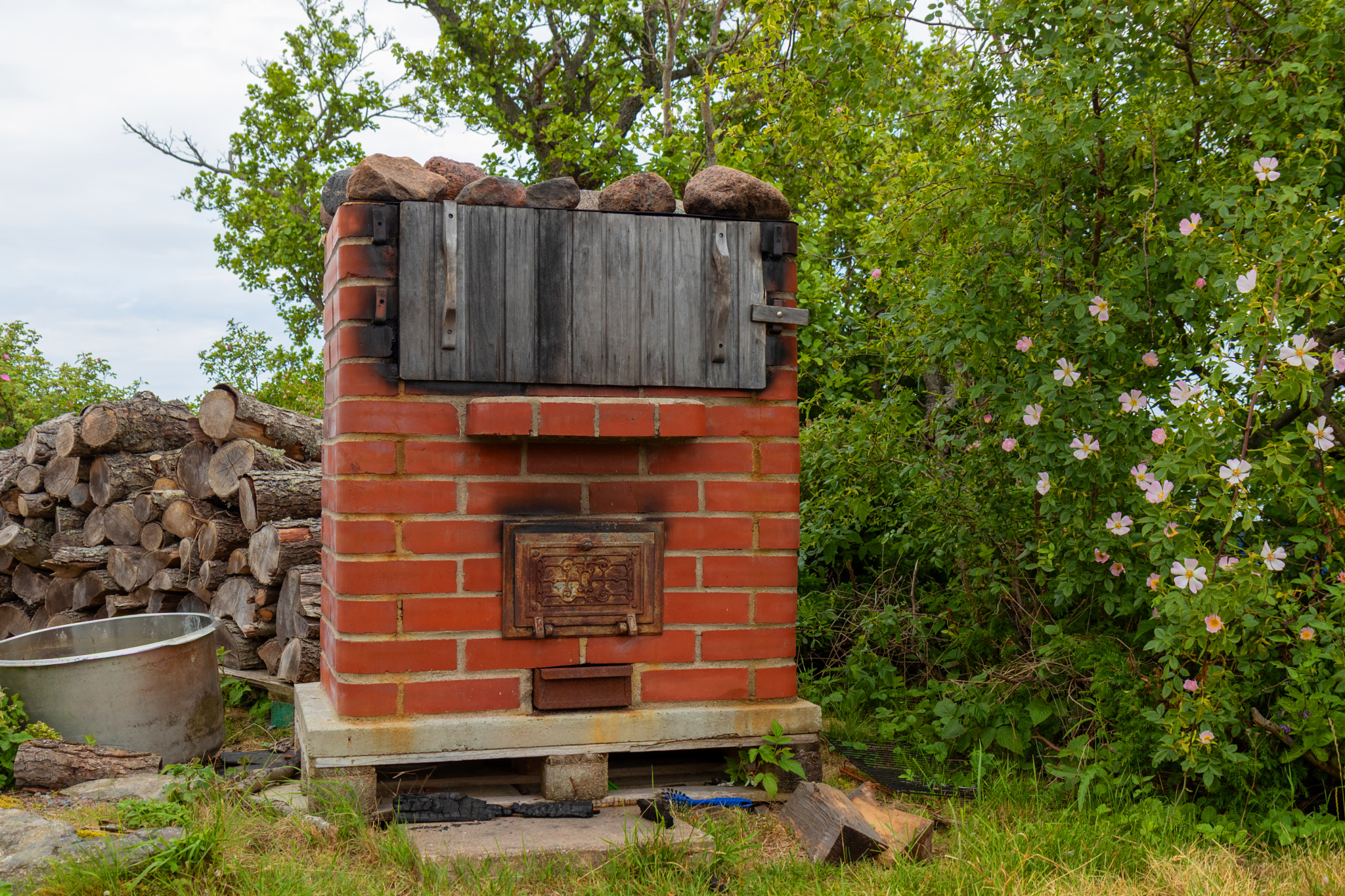 Outdoor red brick smokehouse used for smoking fish, a traditional wood-fired oven structure in rural