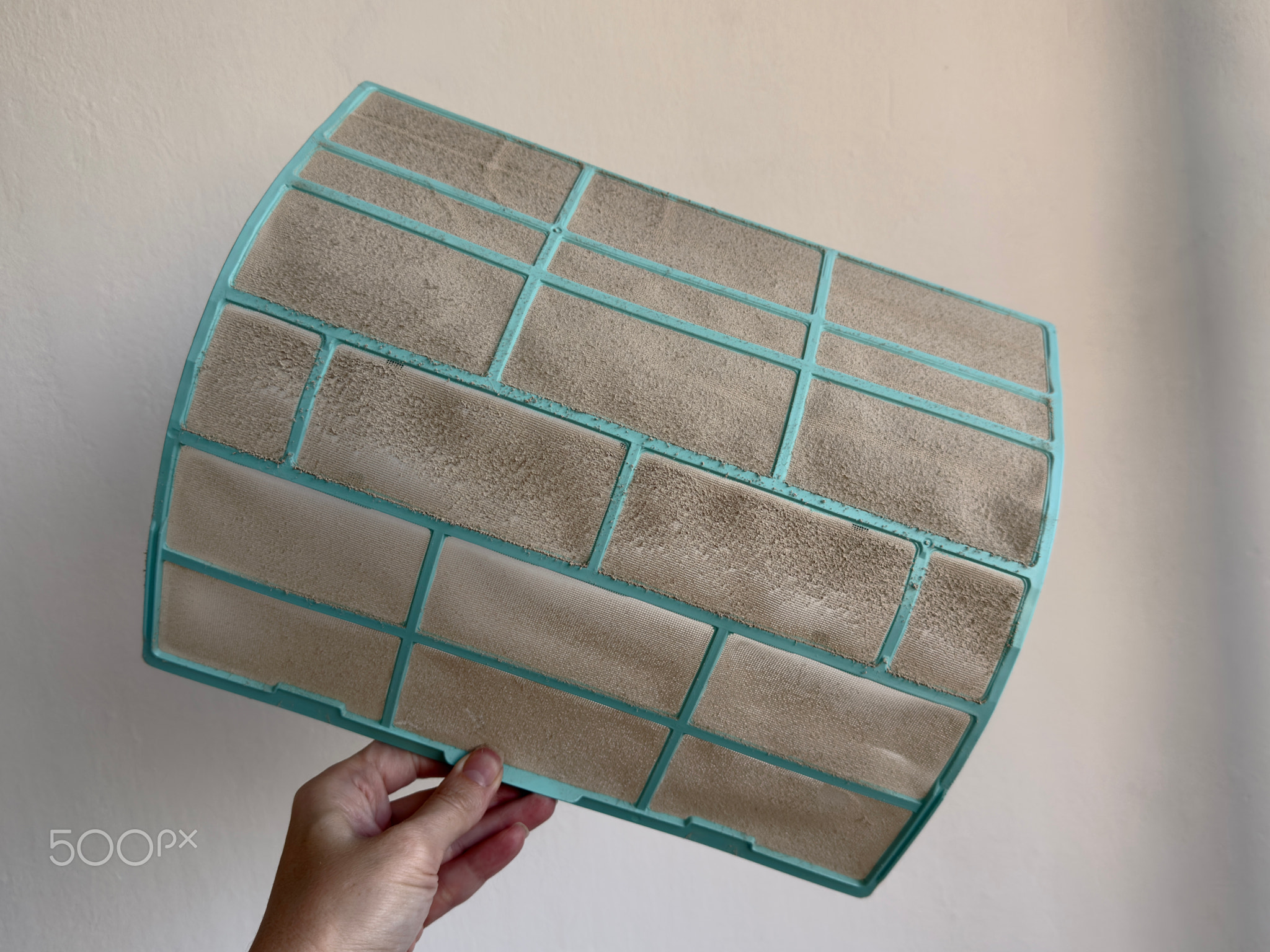 Extremely dusty and clogged AC filter held in hand on white background