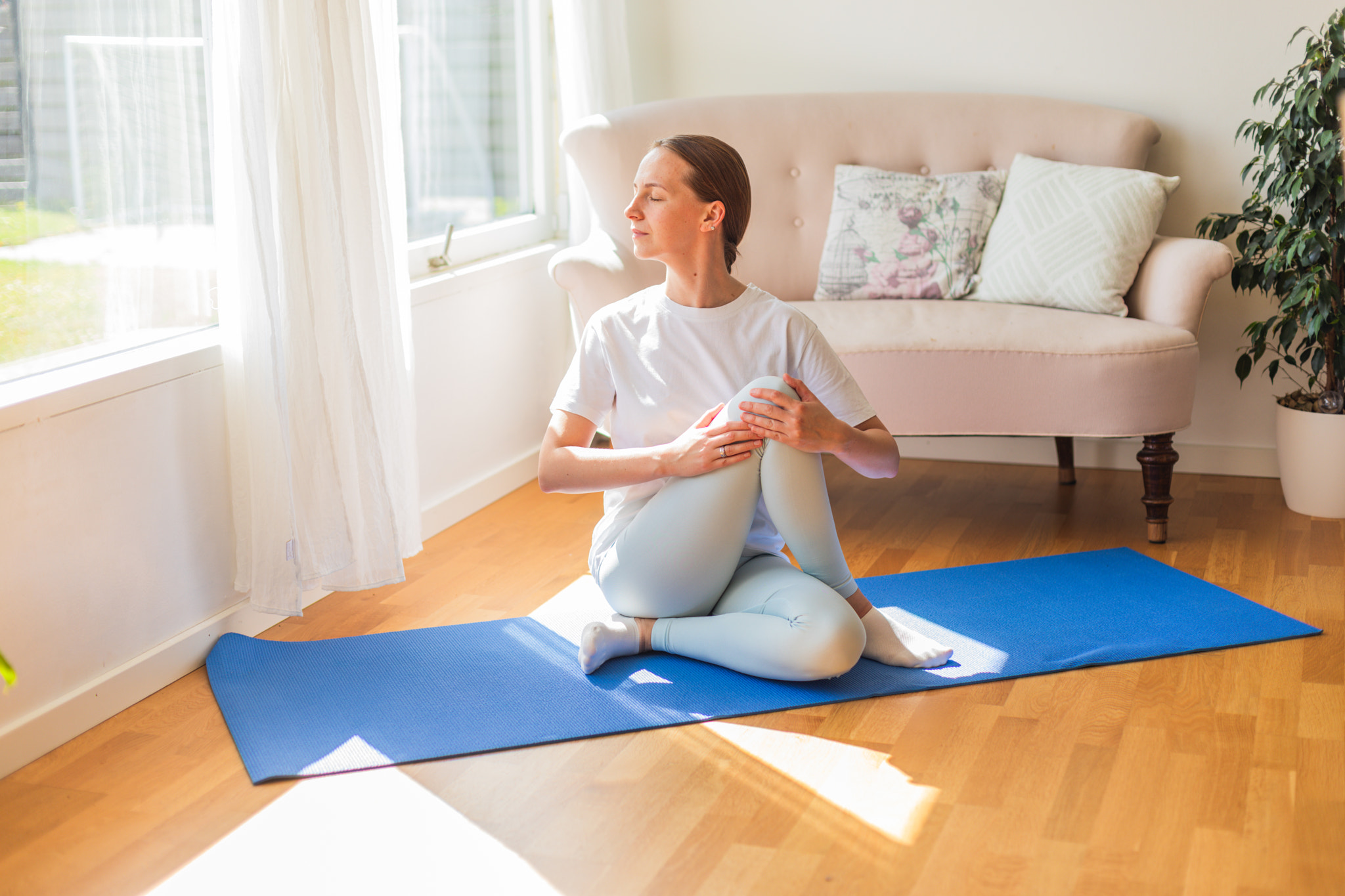 Relaxed woman doing yoga at home in natural sunlight