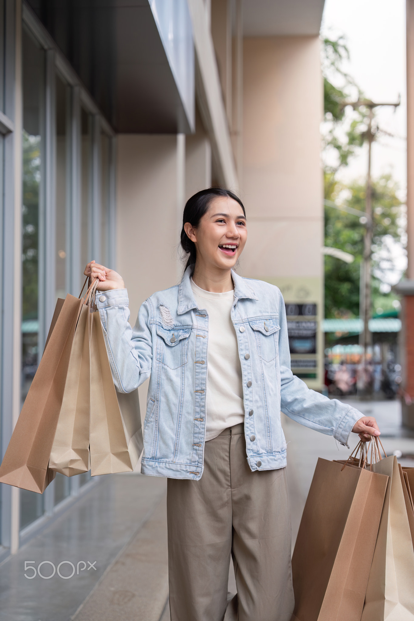 Cheerful Shopper Holding Black Friday Bags in a Commercial Center