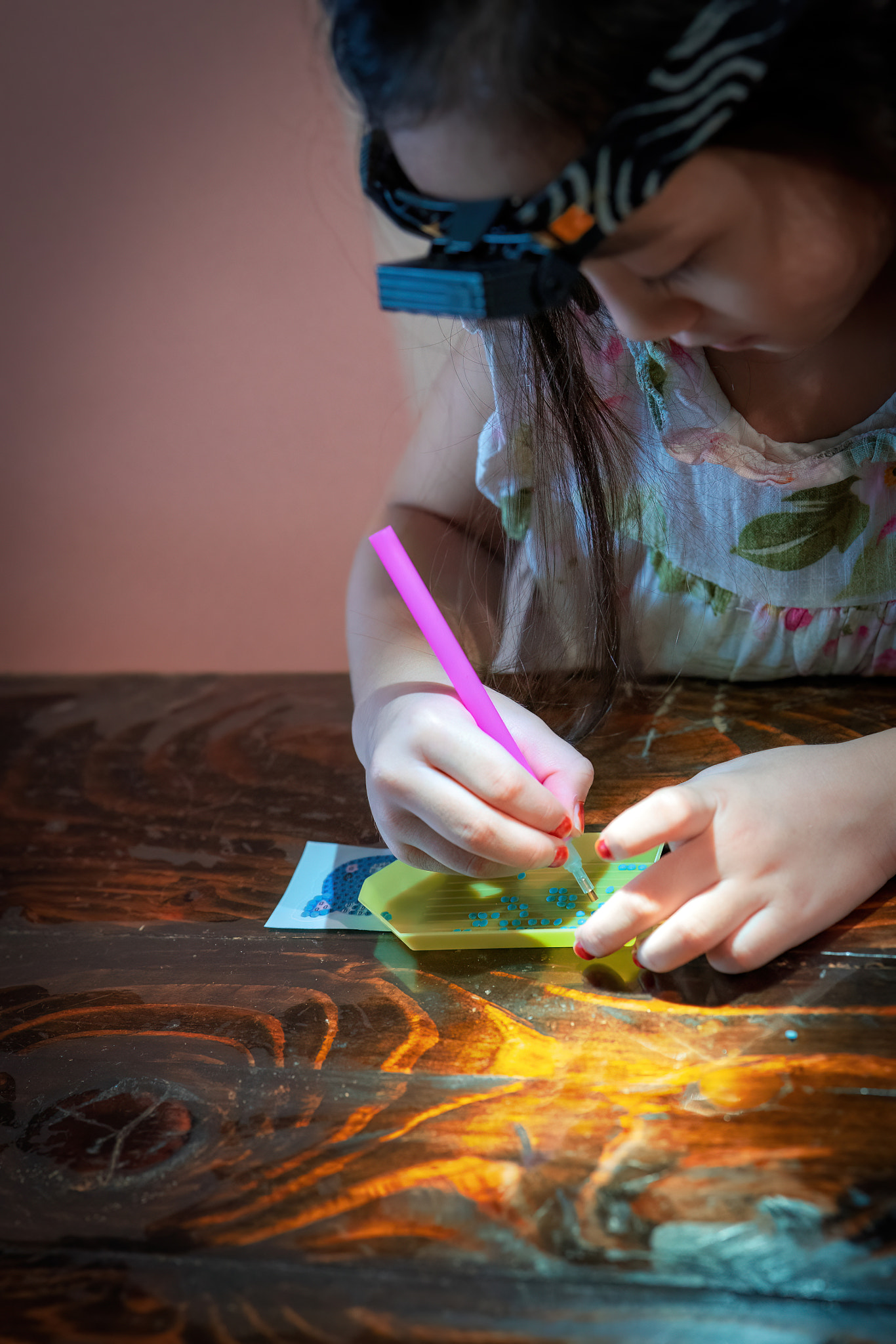Pasting gemstones, a little girl is making artwork with her own hands.