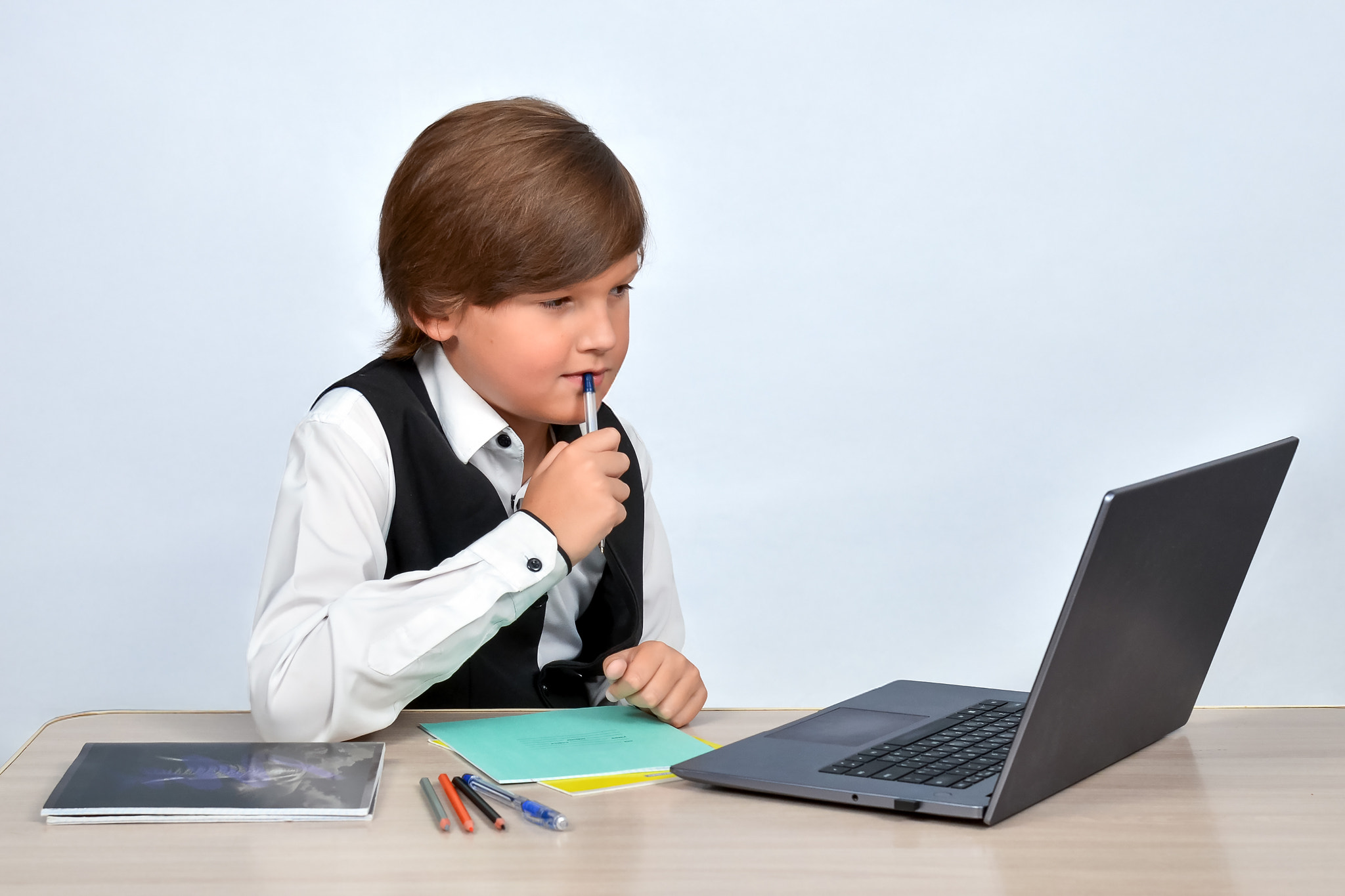 Boy using laptop while sitting against white background
