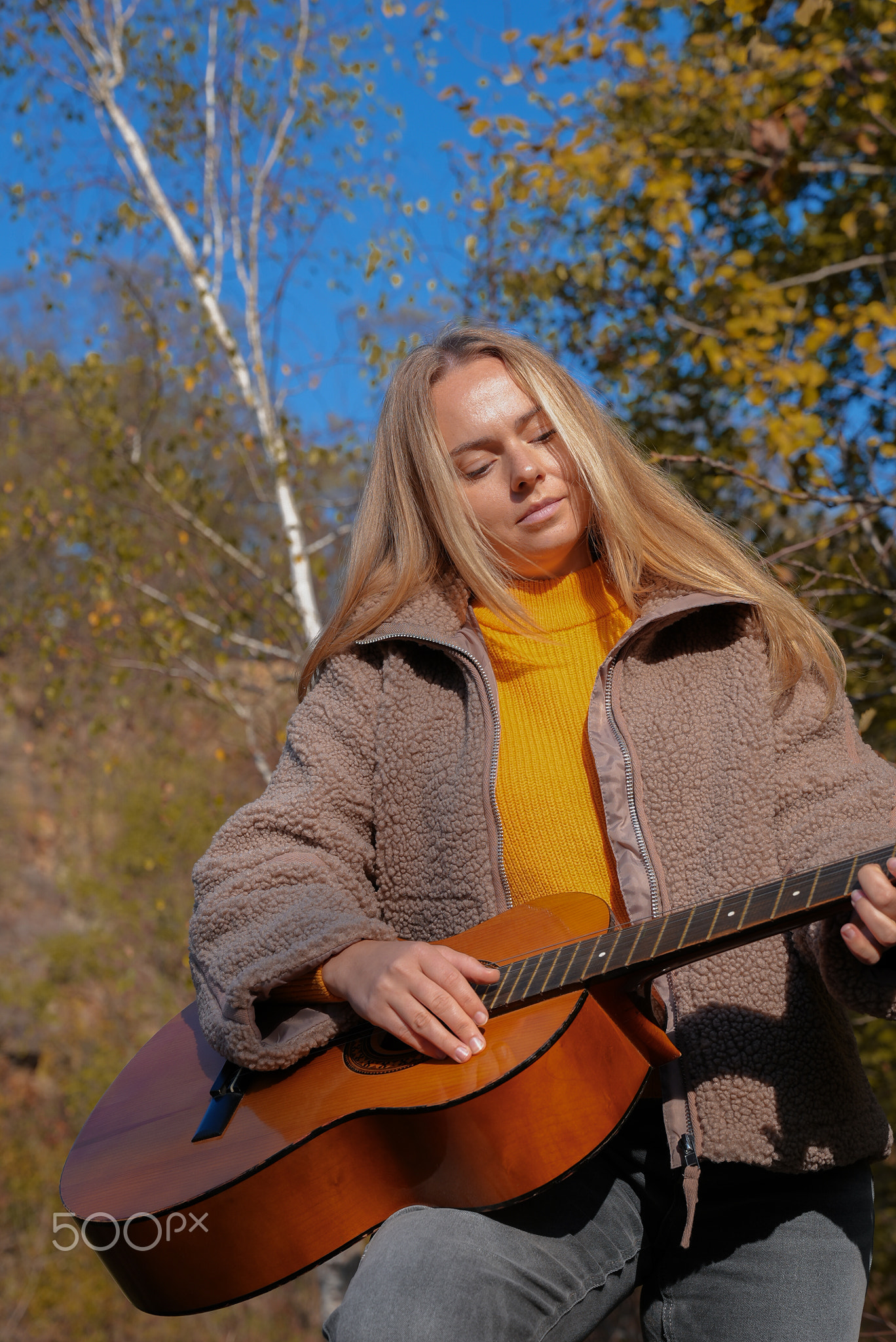 Portrait of smiling caucasian artist plays wooden acoustic guitar in