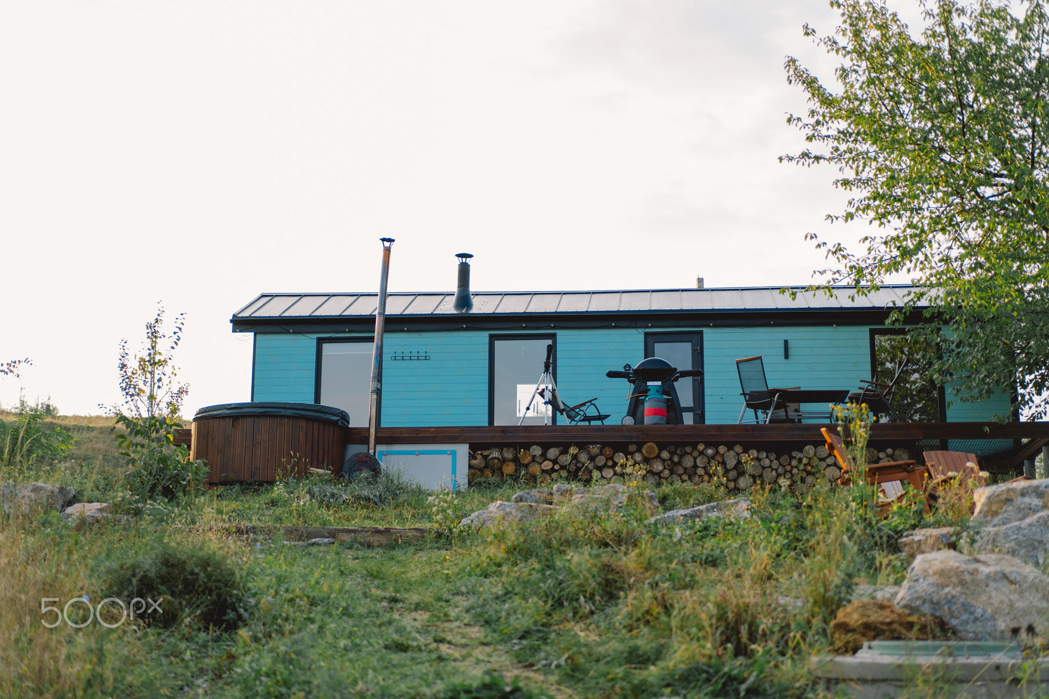 Cozy blue cabin nestled in a tranquil landscape with hot tub in the evening light