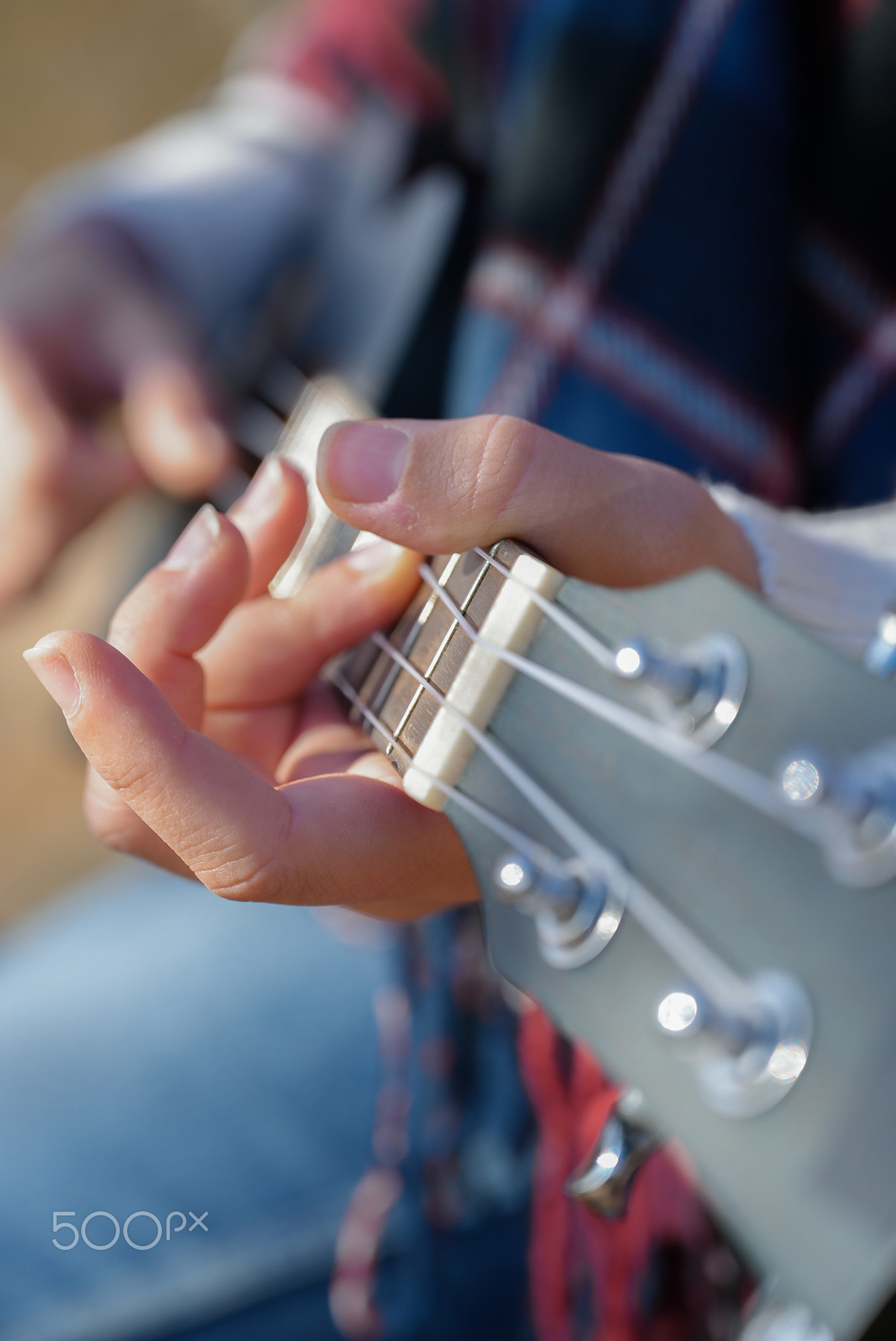 Close up of female hands playing guitar ukulele outdoors in autumn