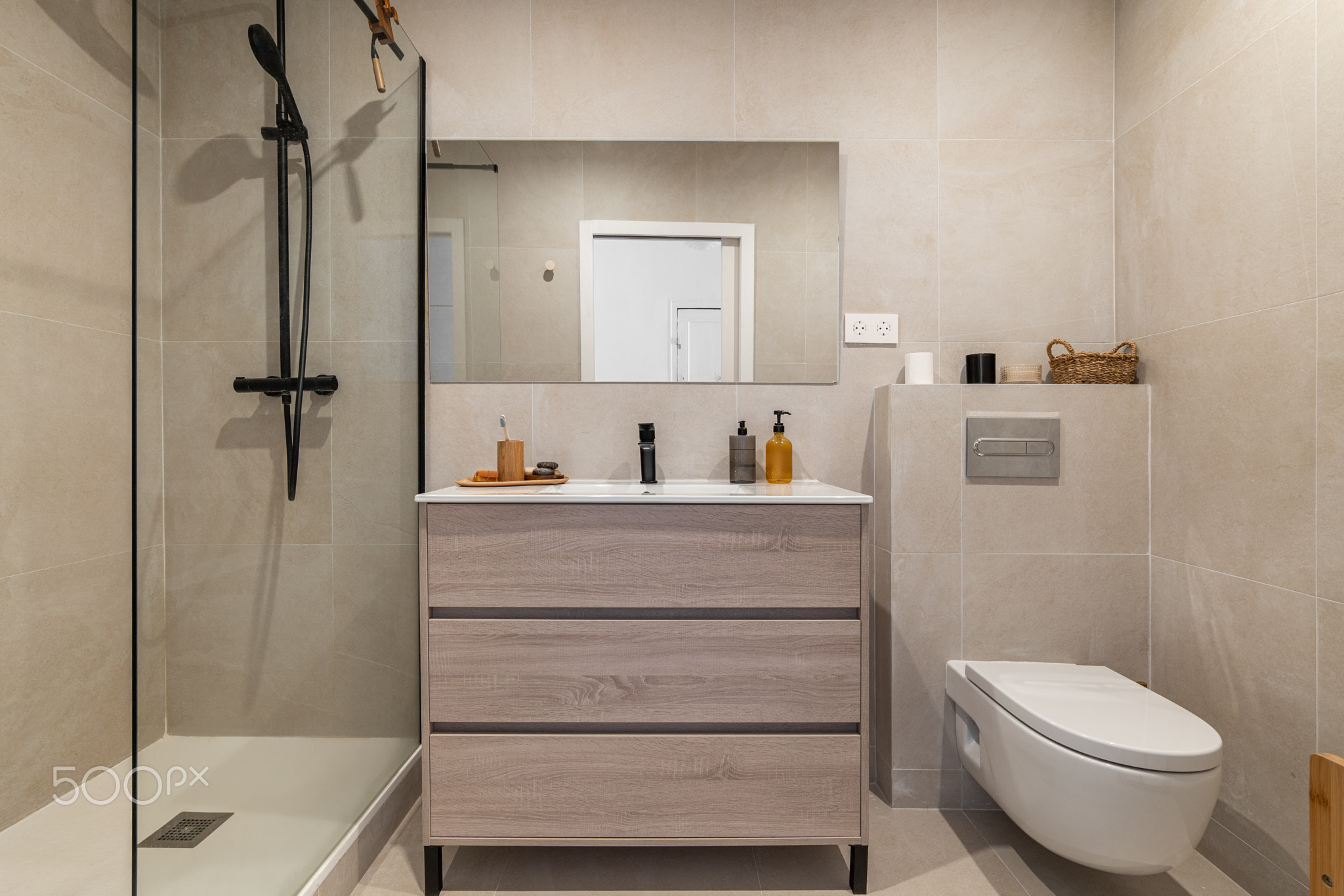 Modern bathroom with a glass shower, wooden vanity, and minimalist decor. Neutral tones create a