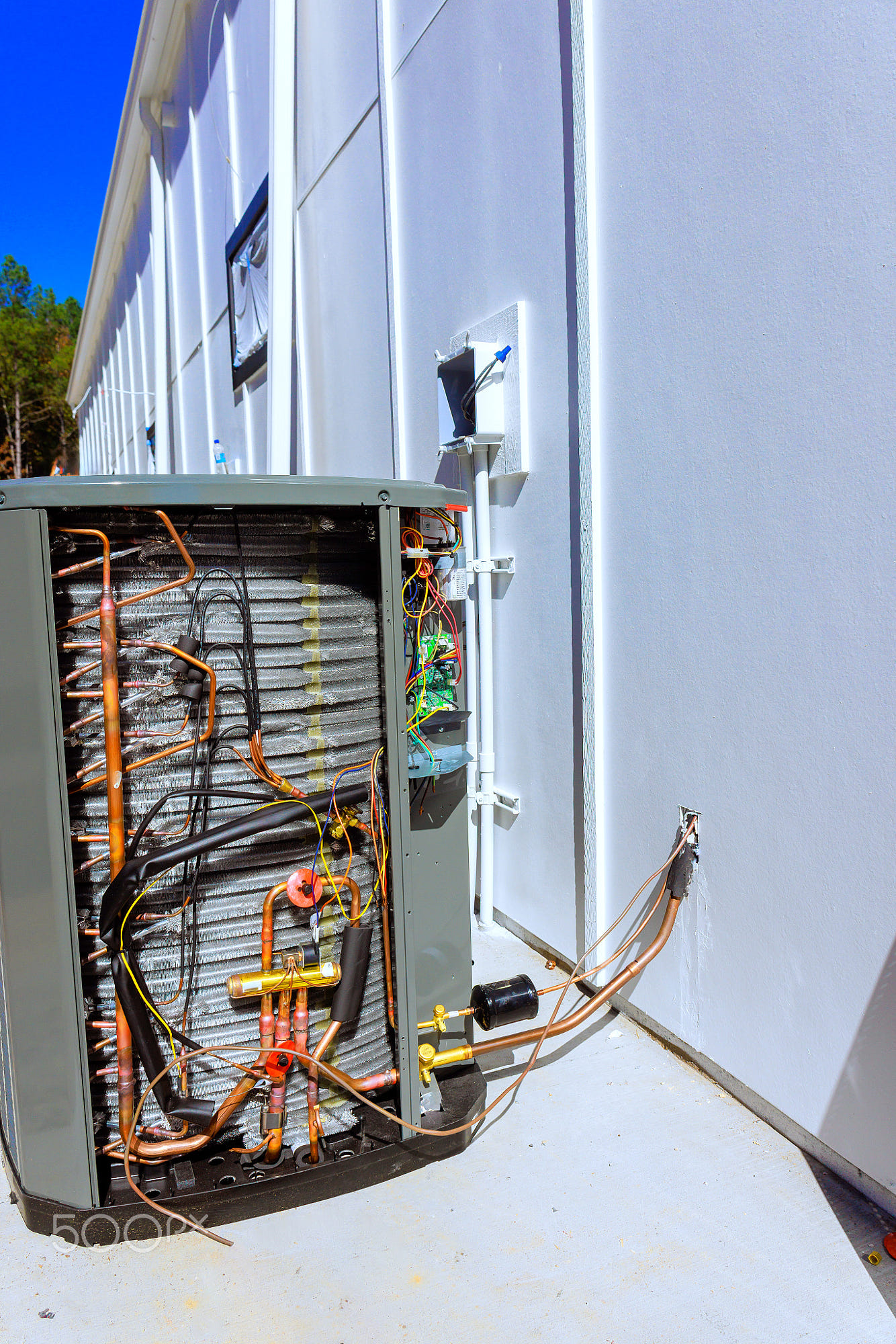 Repair work on an outdoor HVAC unit reveals internal components: Technicians are performing maintenance on an outdoor HVAC unit, exposing its internal components