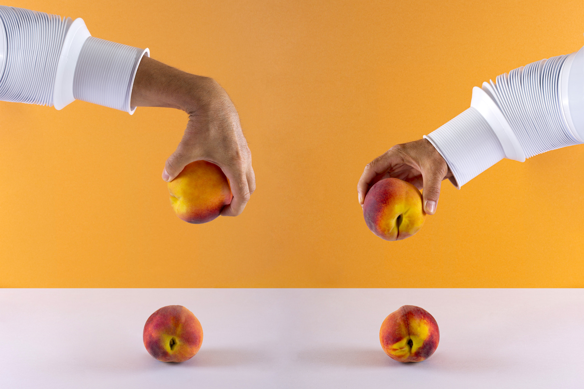 Two male hands with a peach over the table on a colored background