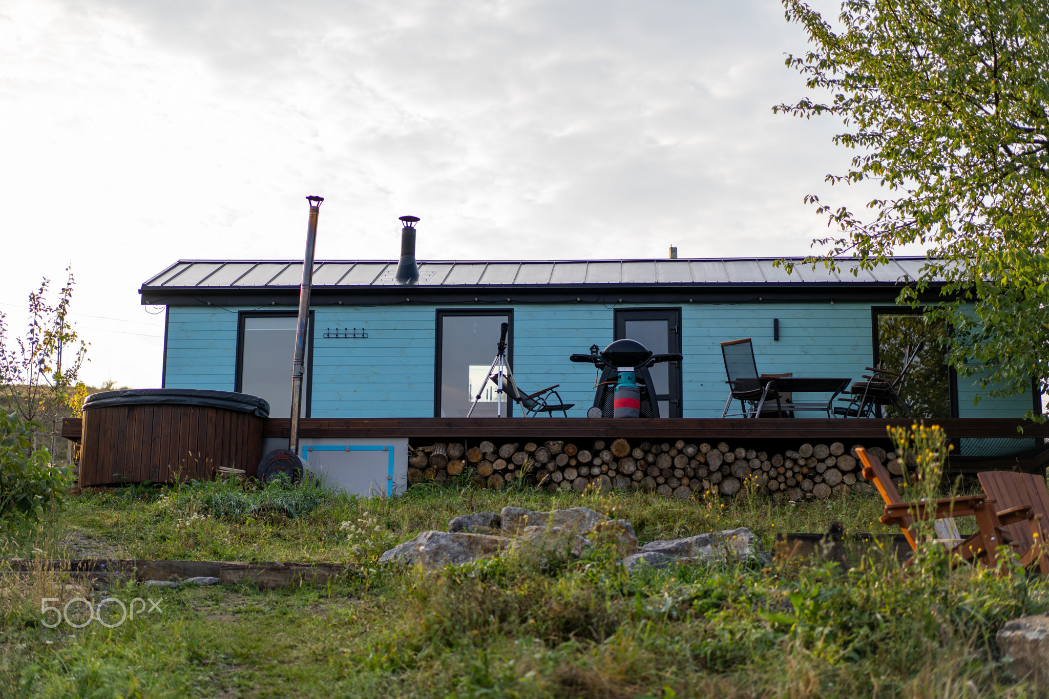 Cozy blue cabin nestled in a tranquil landscape with hot tub in the evening light