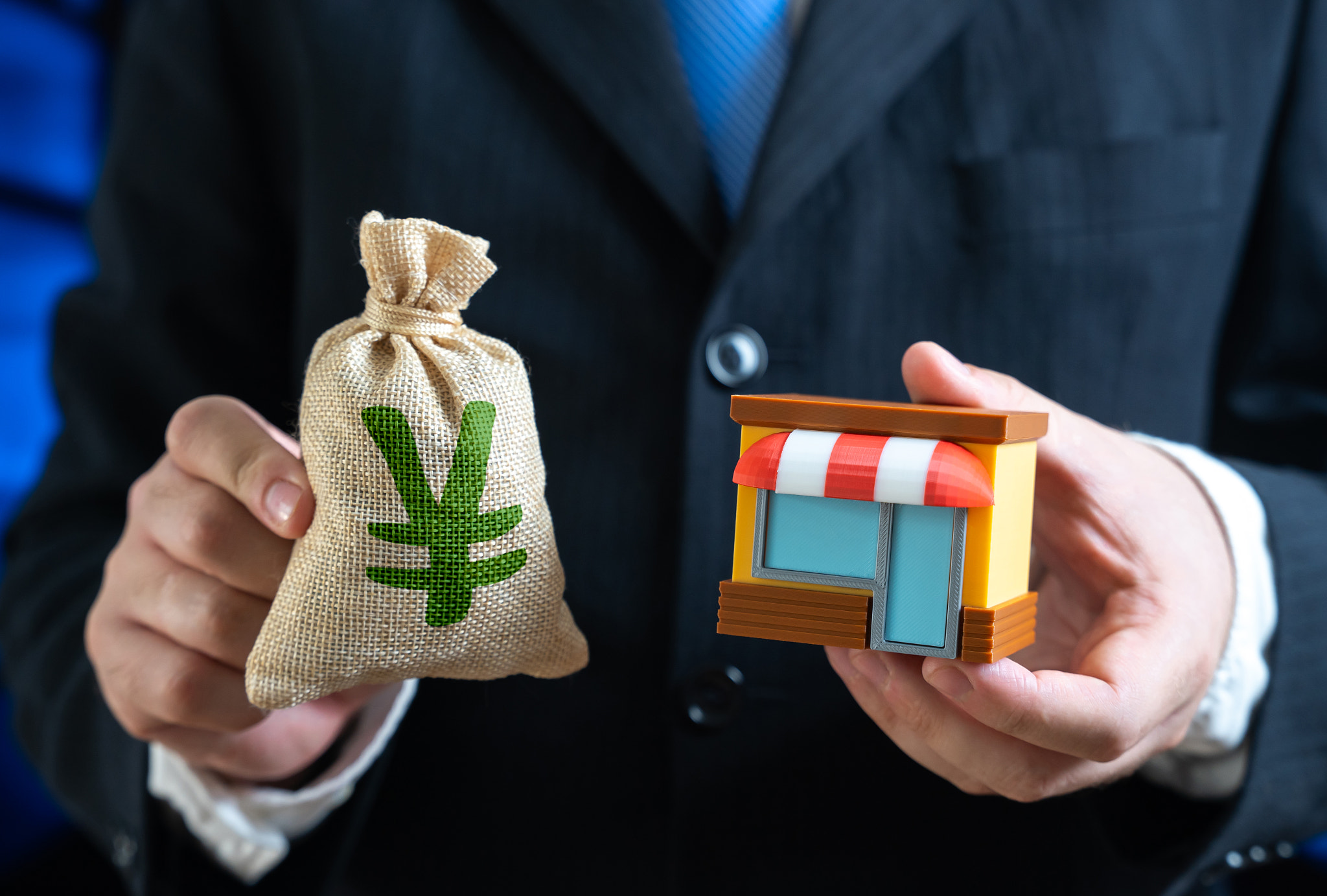 Shop in the hands of a businessman and yen or yuan money bag. Buy a ready-made business. Investments