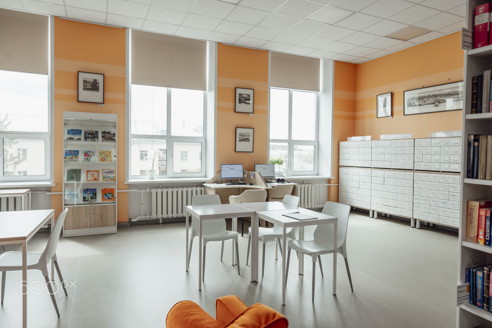 BARNAUL, RUSSIA - AUGUST 7. 2025: modern library with orange walls. It features white tables, chairs