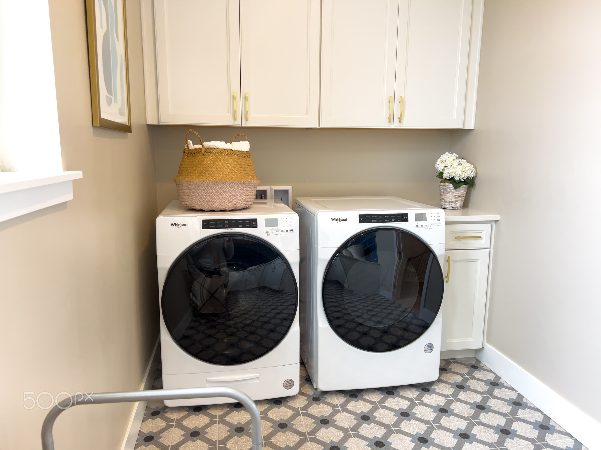 Bright laundry area with white cabinets and decor