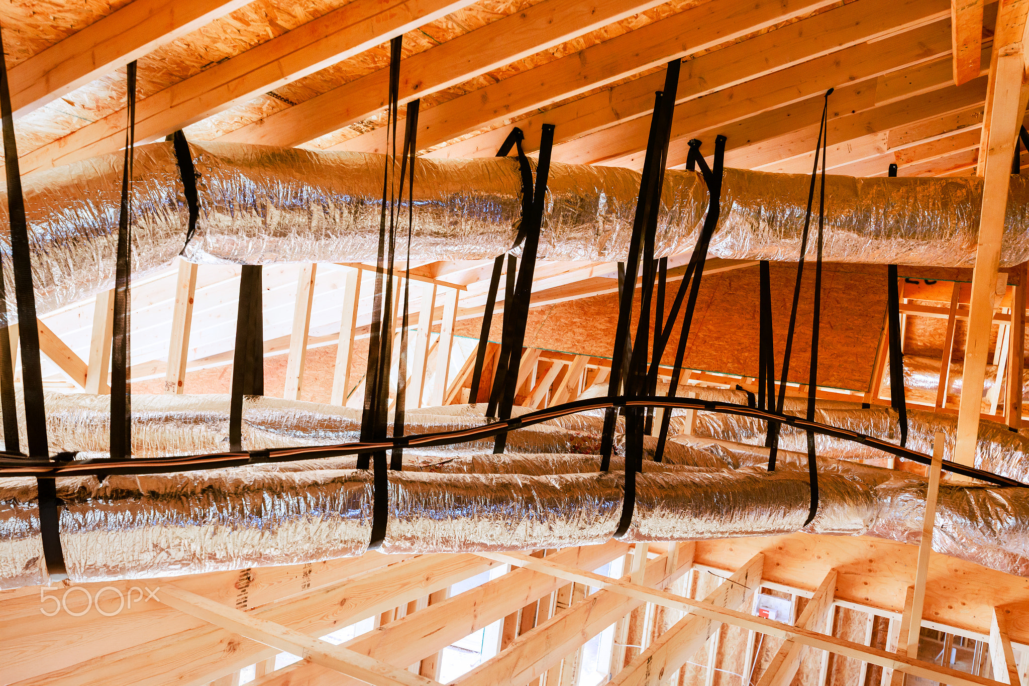 Workers install ductwork in new building under construction