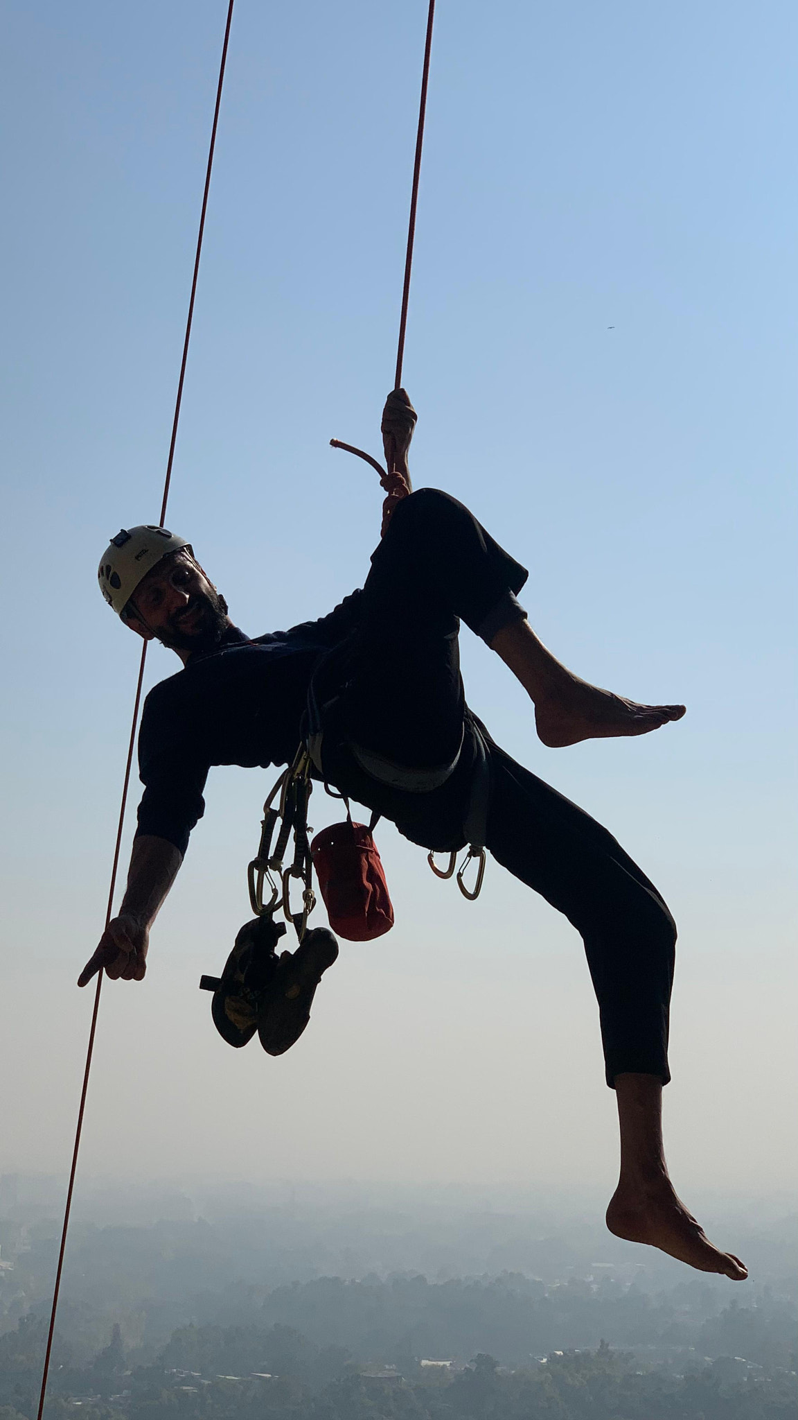 Low angle view of man zip lining against clear sky