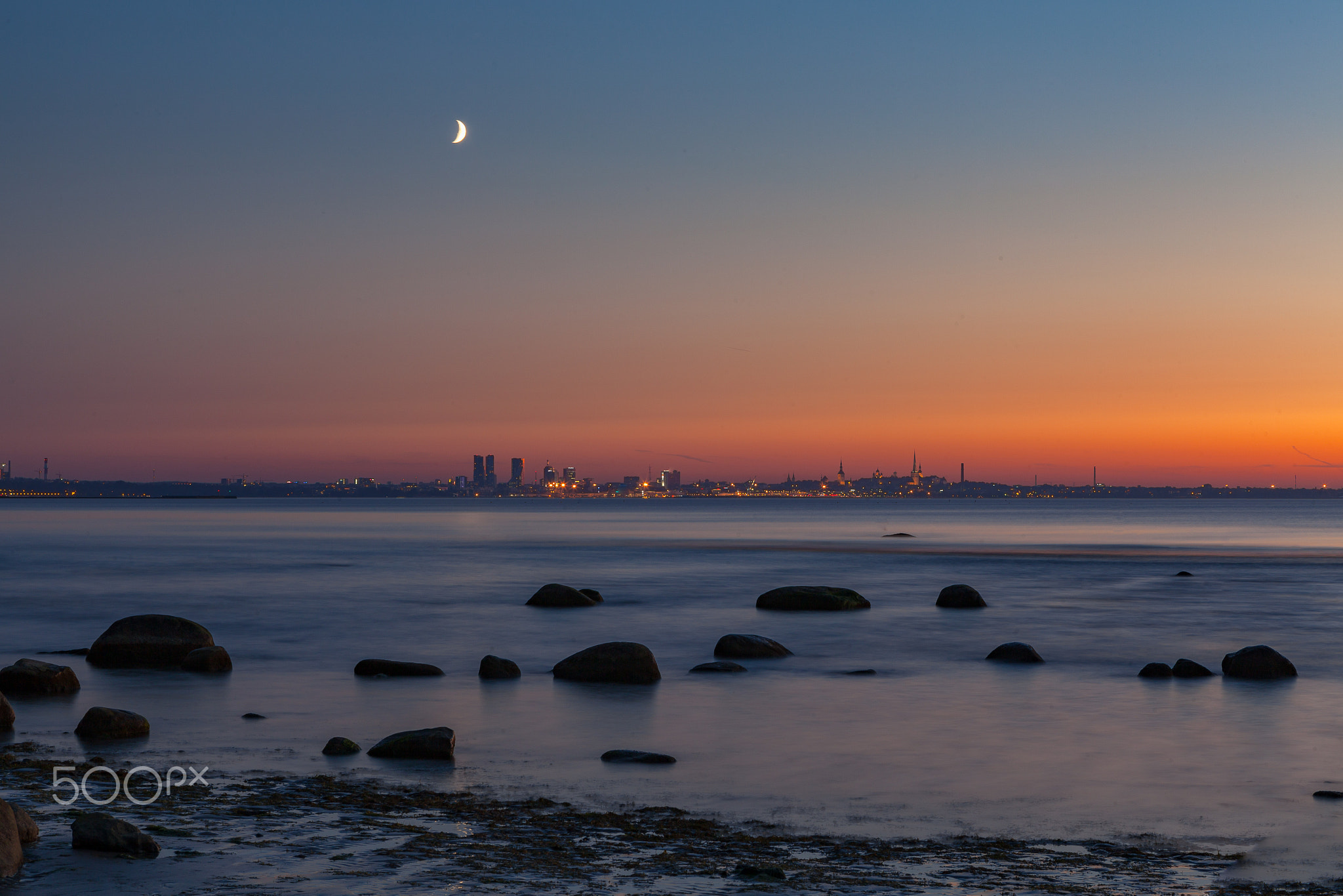 Sunset seascape with boulders on the shore of Baltic sea. Amazingly colorful sky.