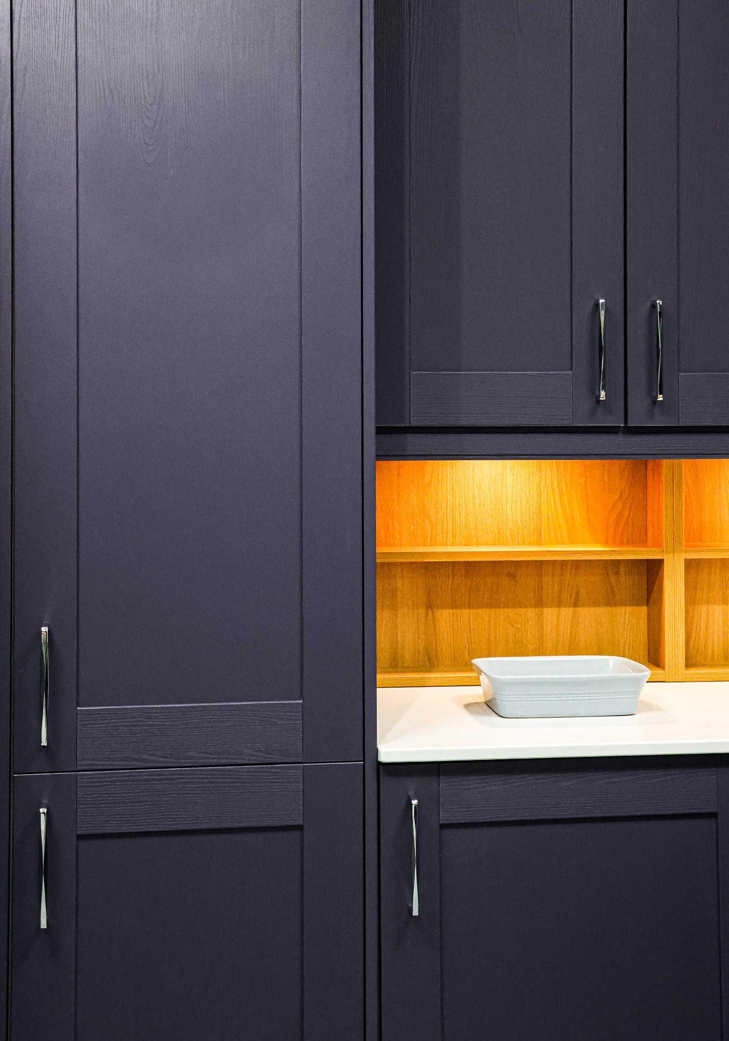 Contemporary home kitchen interior featuring dark purple wood cabinets, white countertop and warm il