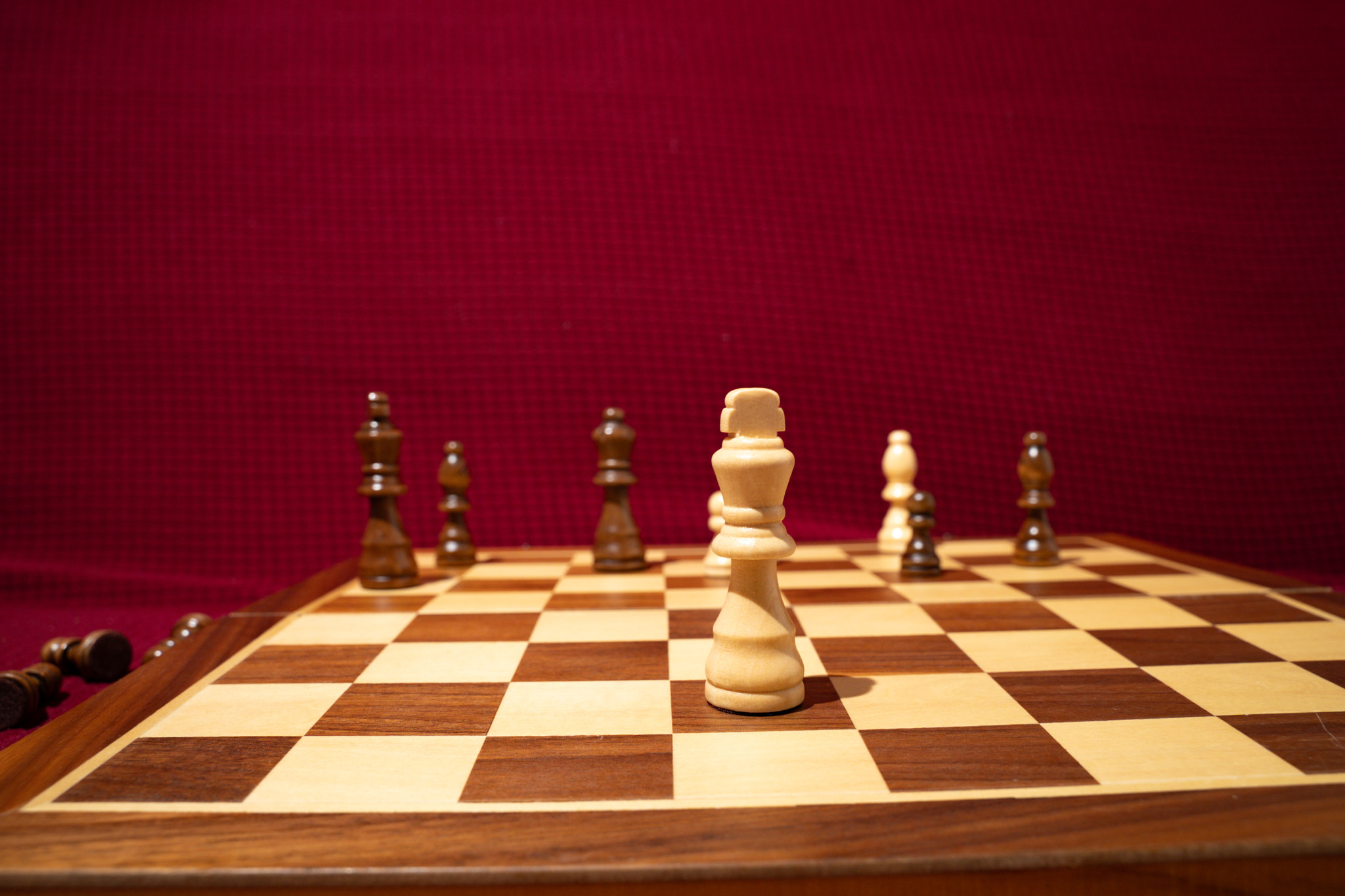 White queen on wooden chessboard with other pieces in the background