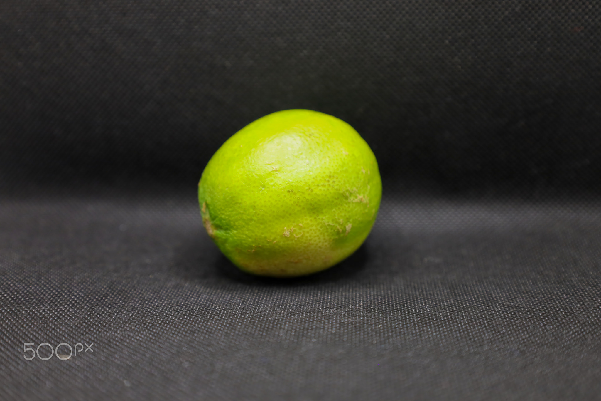 Fresh green lime resting on a dark fabric background, capturing the vibrant essence of healthy ingre