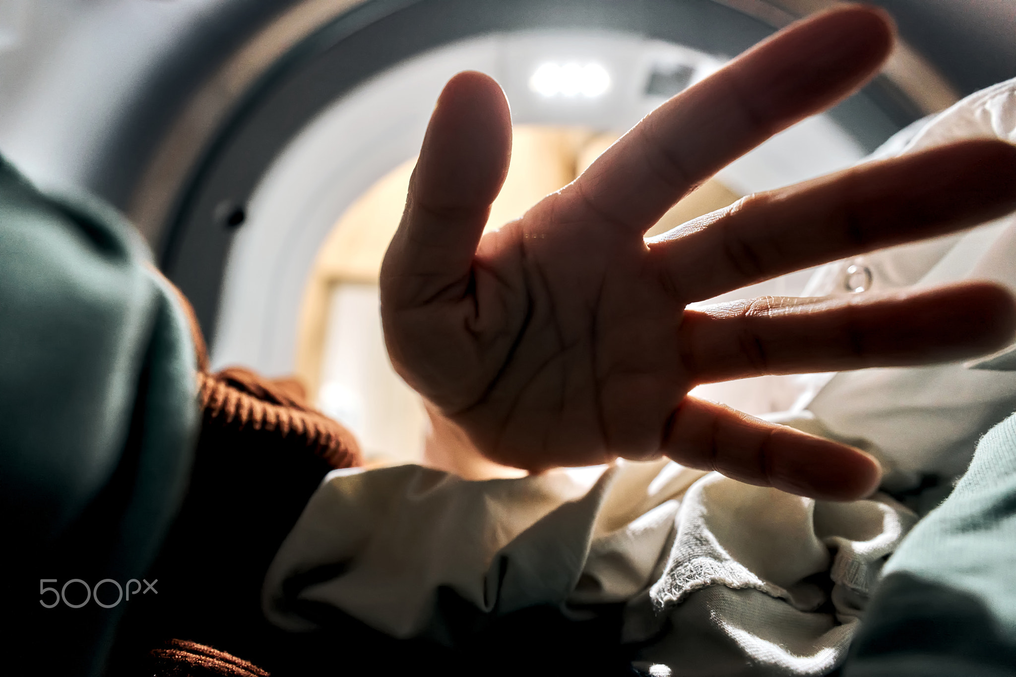 Hand reaching into washing machine for laundry