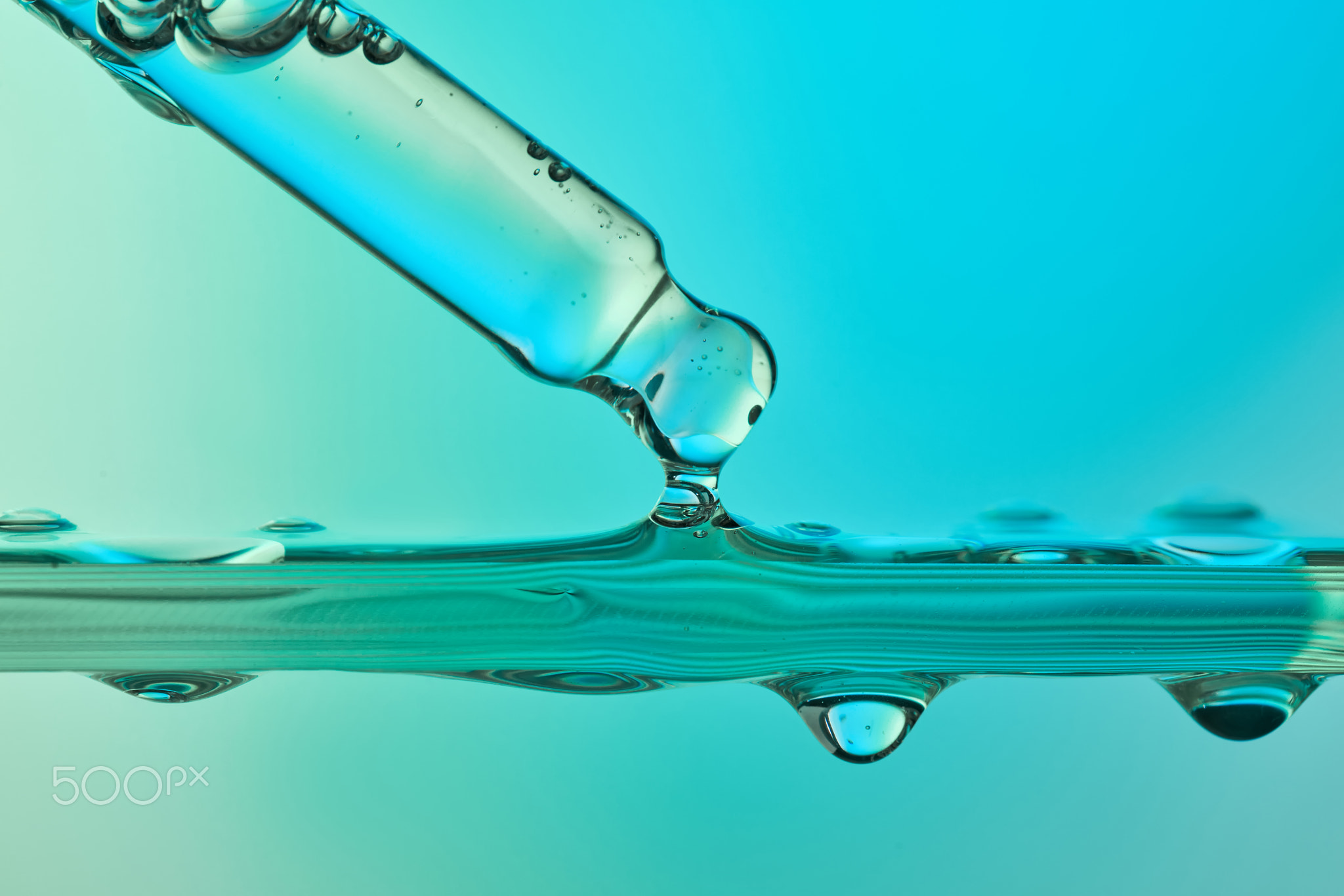 Pipette dripping blue liquid in science lab