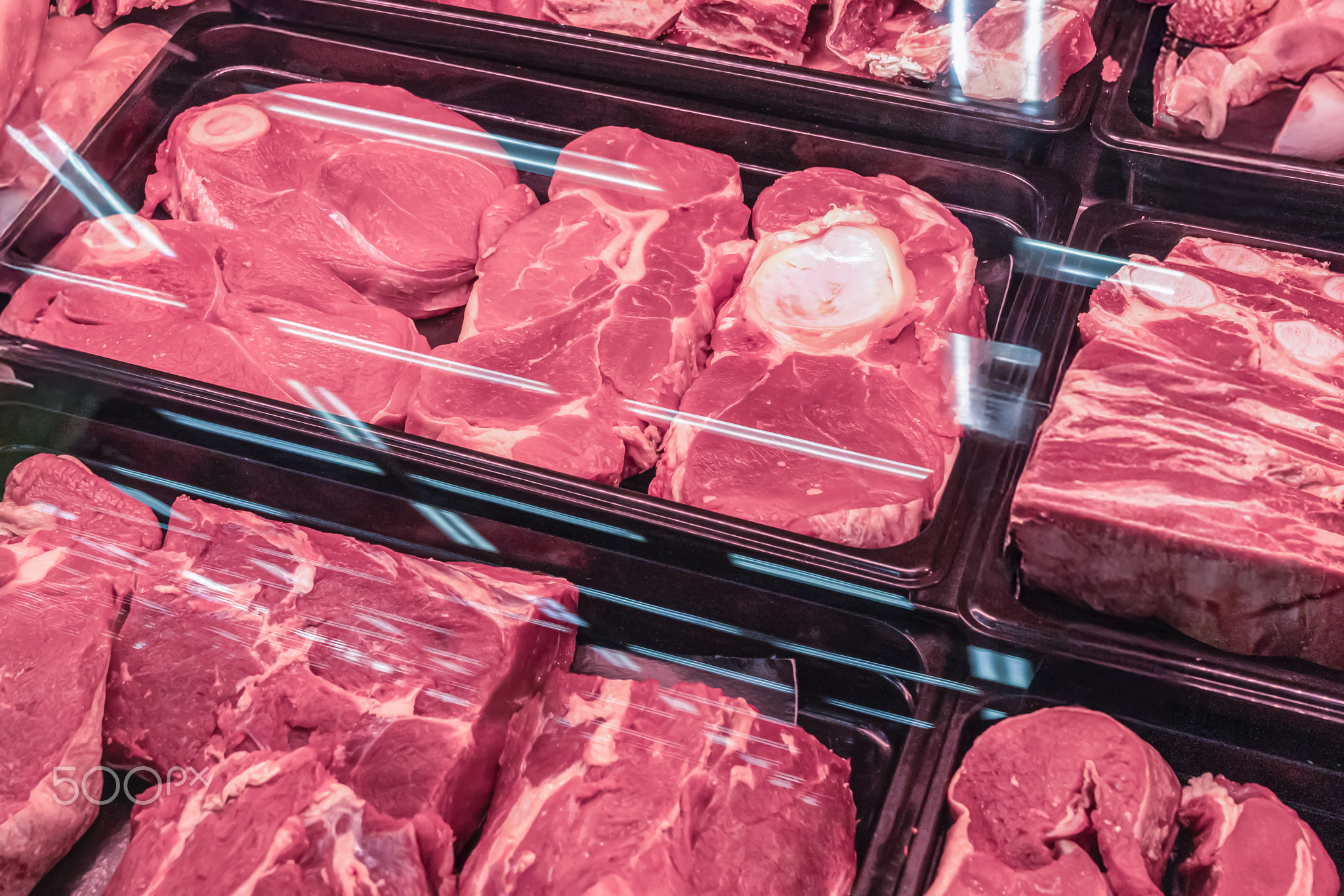 Fresh red meat, chilled, beef fillet in close-up on a shop window with red lighting. Meat