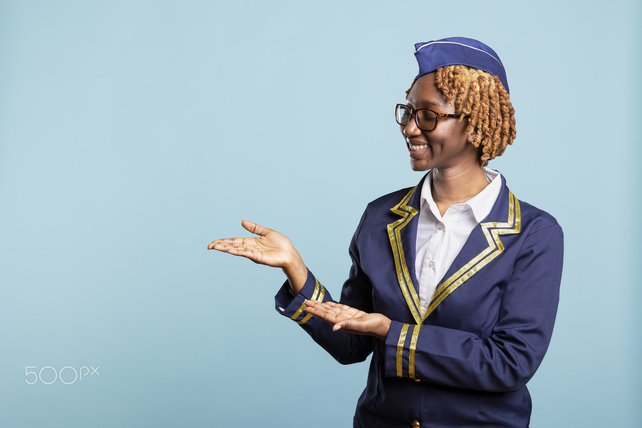 Smiling air hostess in uniform gesturing toward blank copy space