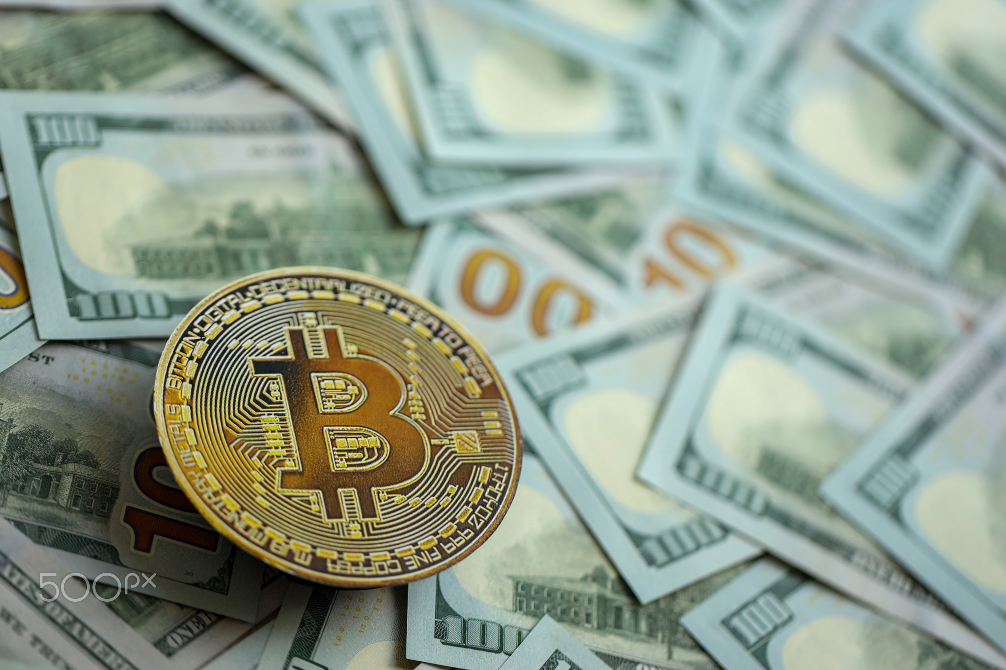 Bitcoin BTC coin on big amount of hundred US dollar bills