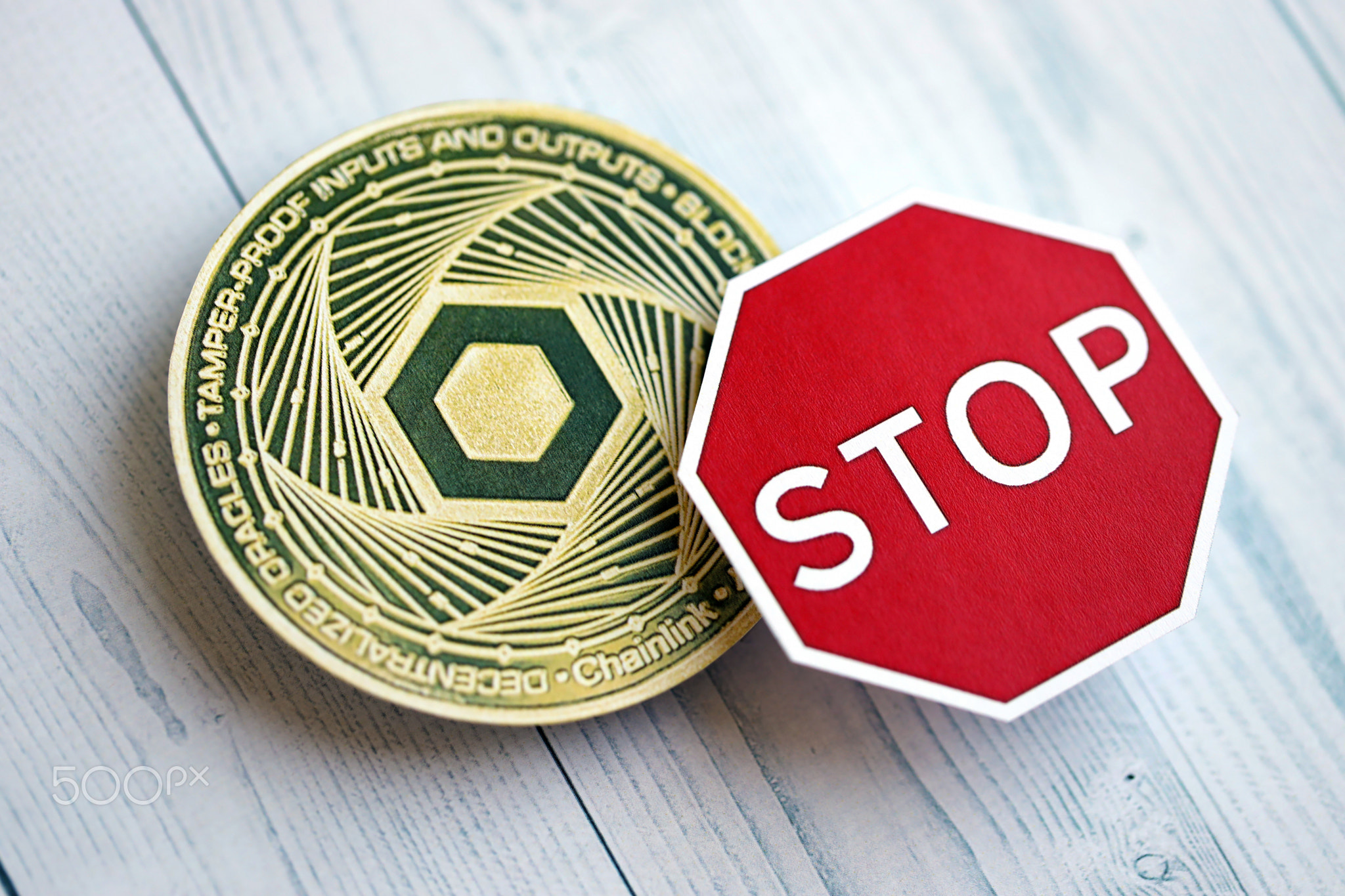 Chainlink LINK coin and red paper stop sign on wooden background