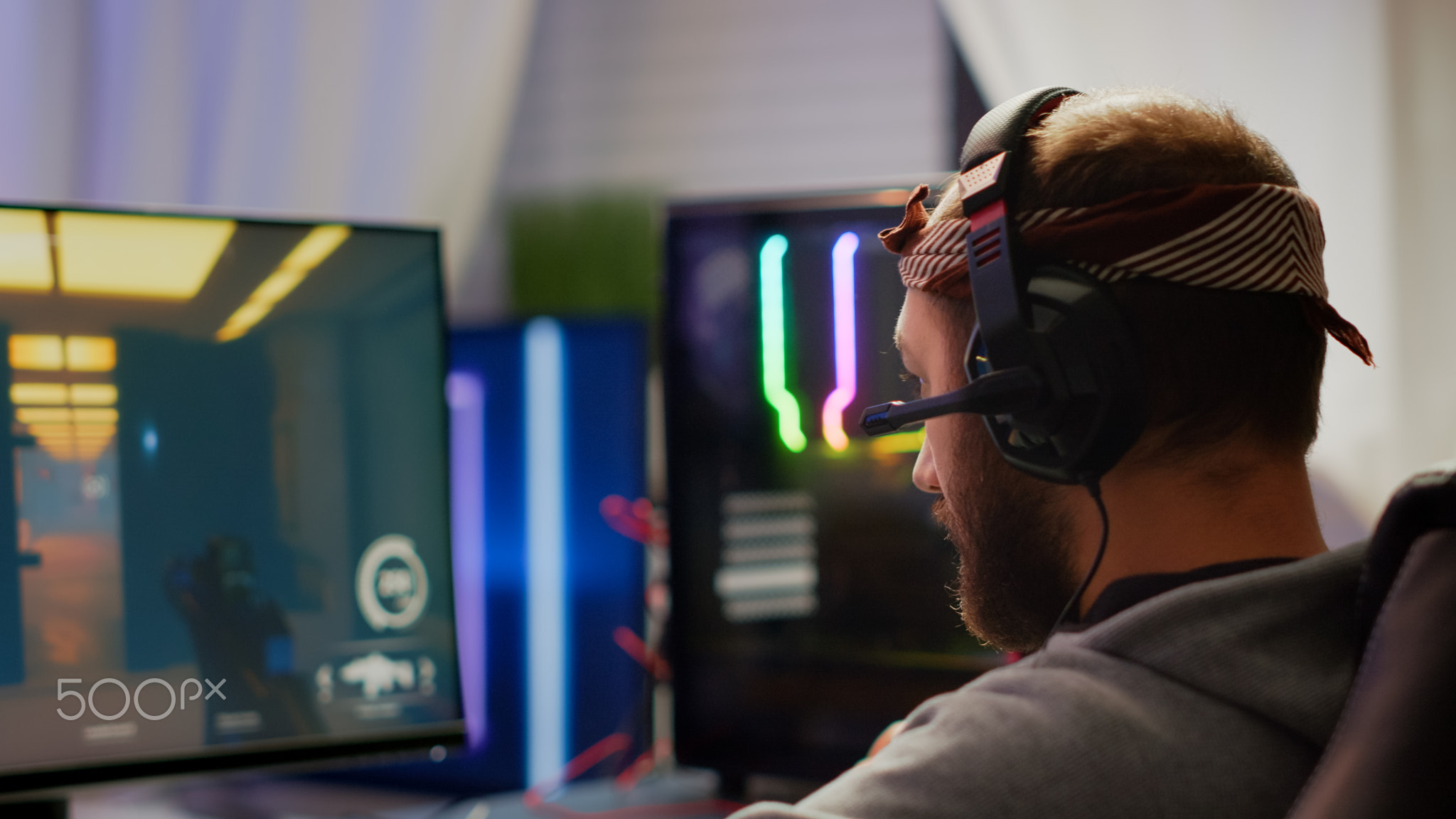 Focused man gamer putting headset playing shooter online video game