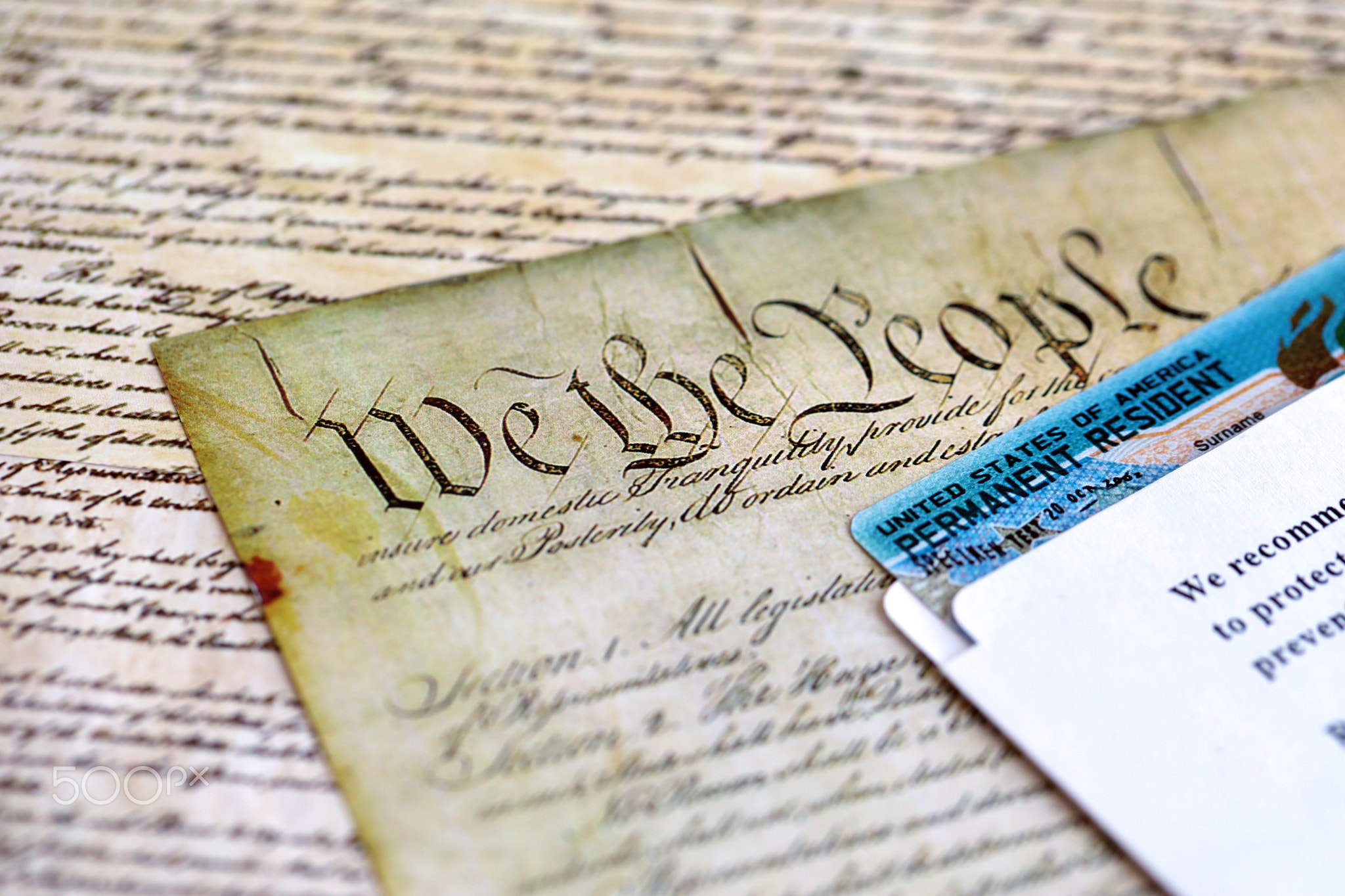 Permanent resident green card in envelope lies on US constitution page
