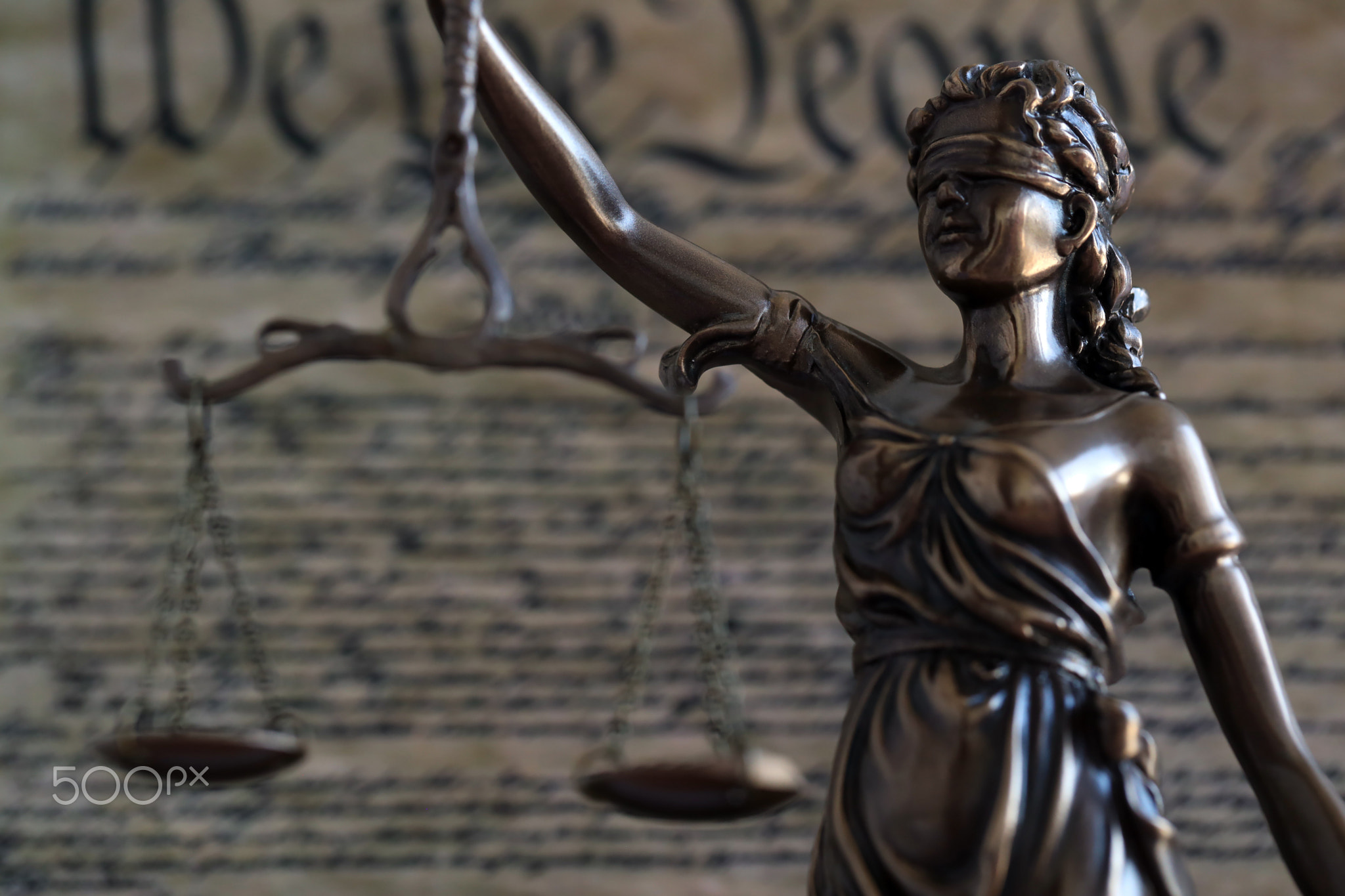 Lady Justice and background of US Constitution page. Lawsuit and judgement in US