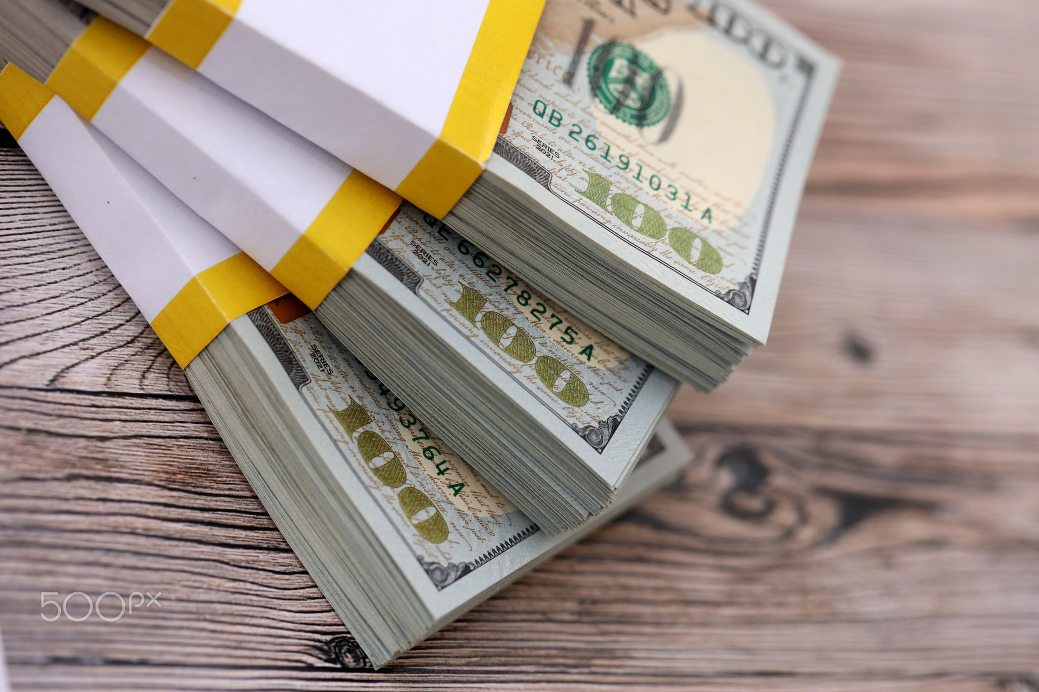 Three packs of ten thousand US dollar bills on wooden background. Packs of hundred dollar bills