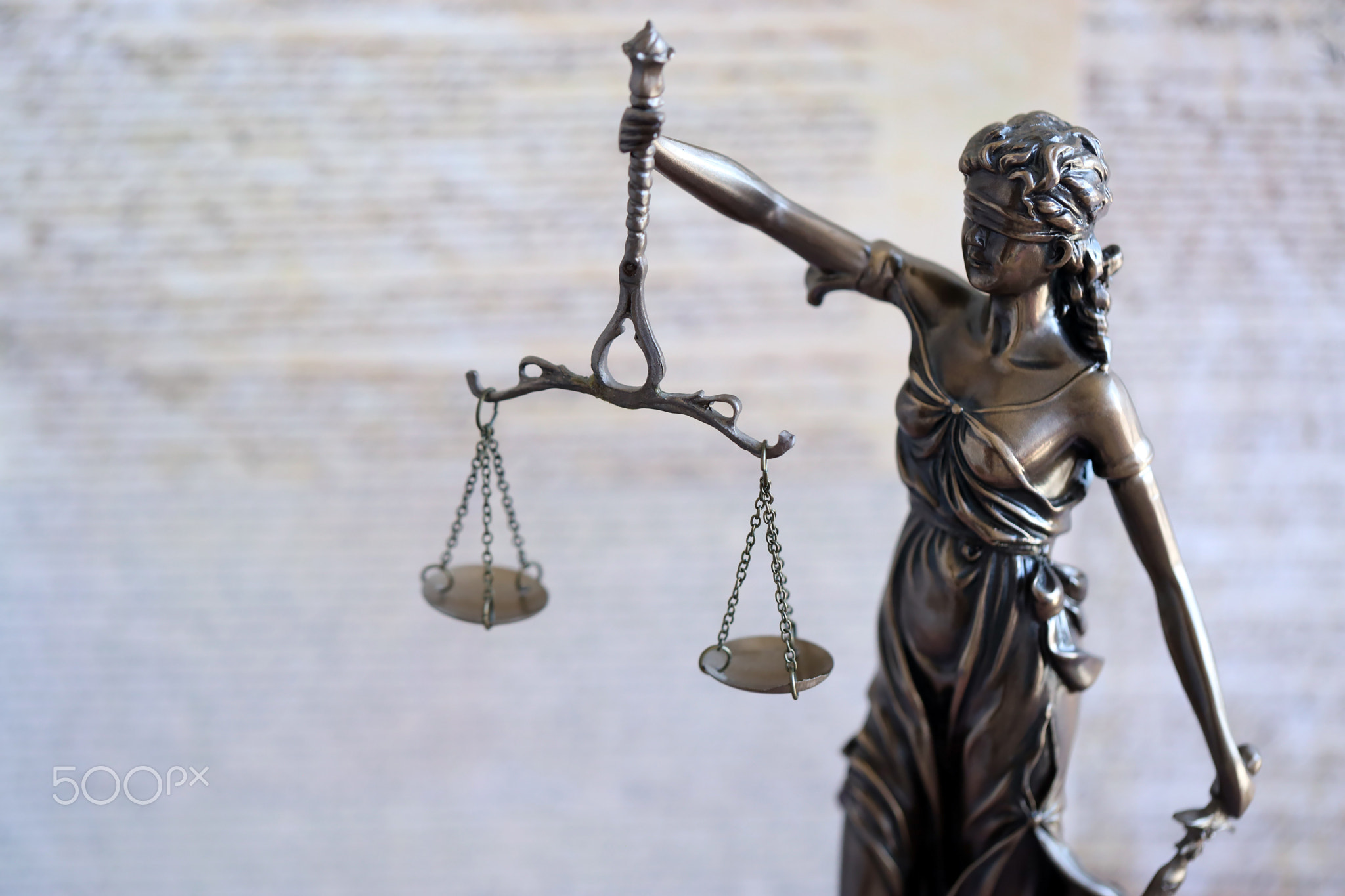 Lady Justice statue with scales on background of US Constitution. Lawsuit and punishment in US